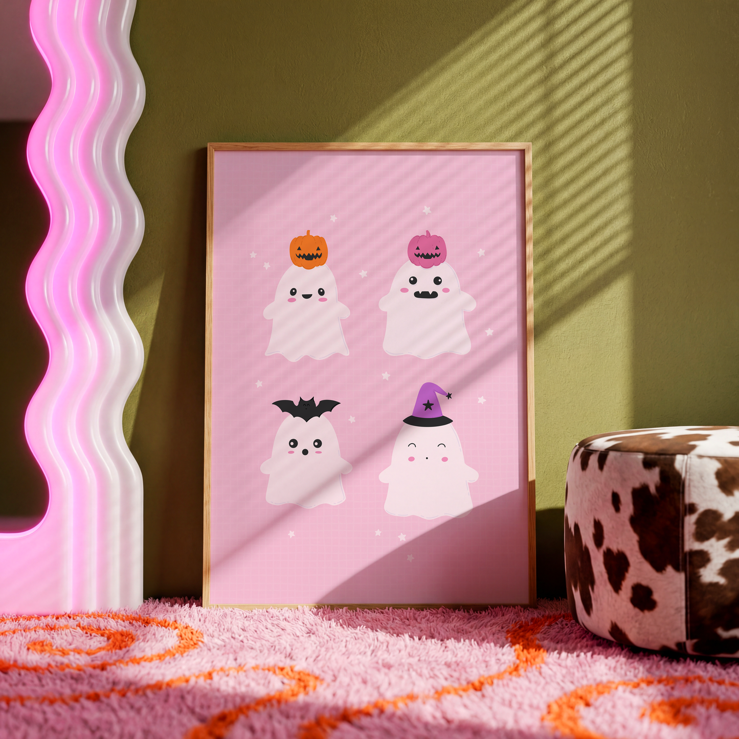 A pink Halloween illustration print featuring four cute ghosts with different Halloween themed hats on their heads.