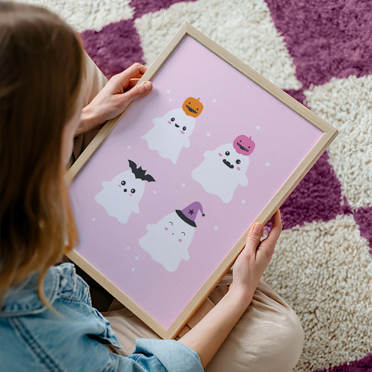A pink Halloween illustration print featuring four cute ghosts with different Halloween themed hats on their heads.