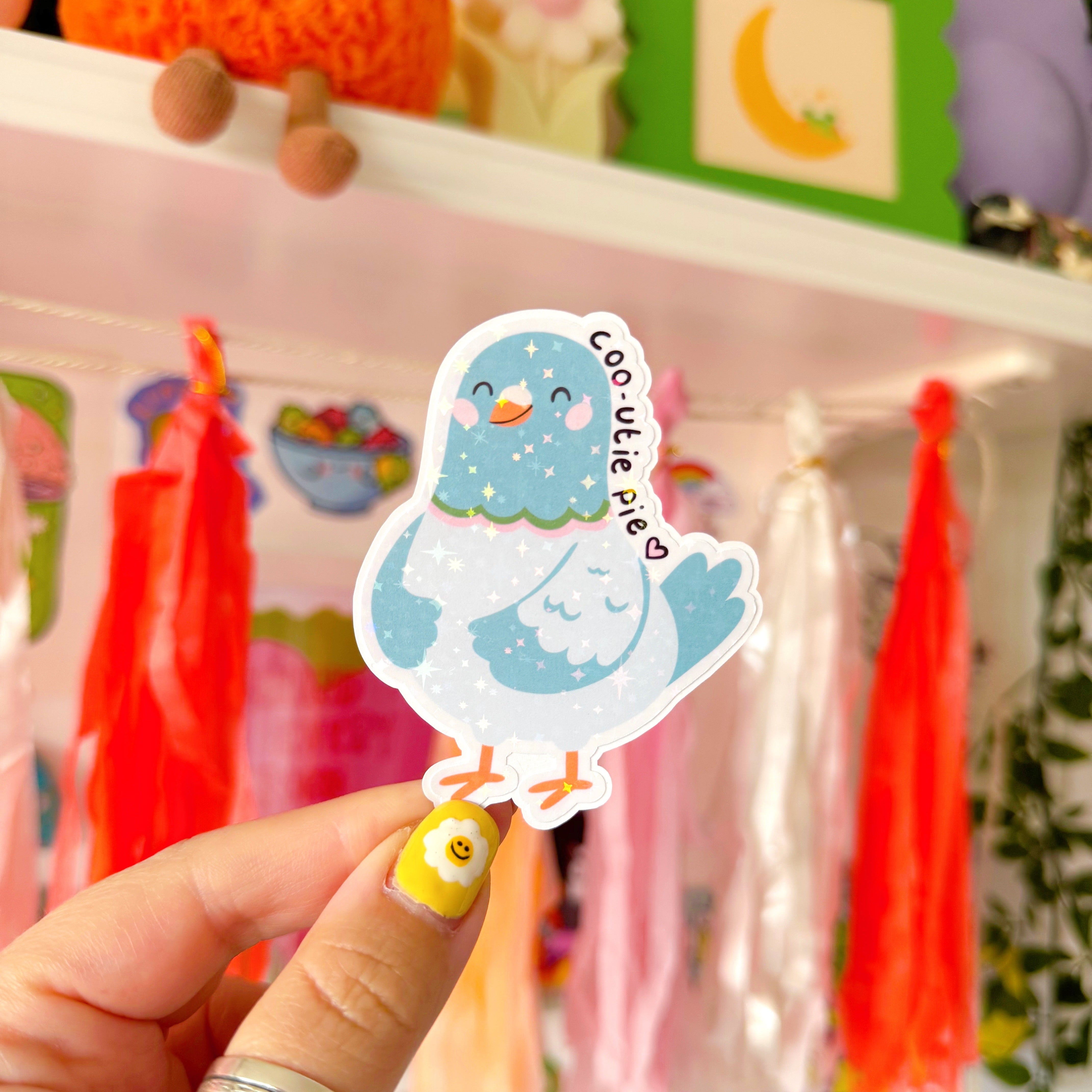 A sticker of a pigeon, with a cute smiling face. Around the head of the pigeon is text that reads 