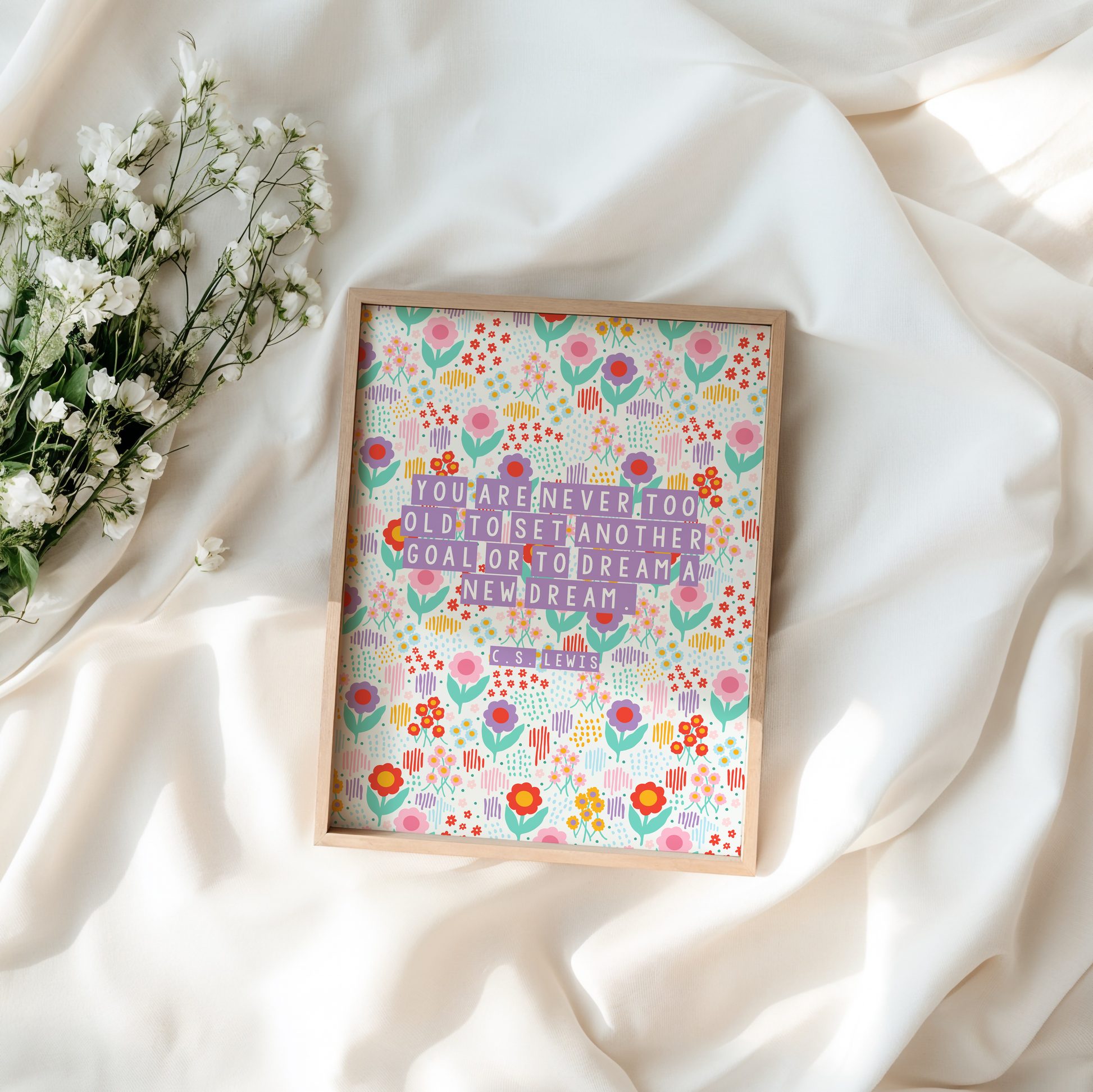 A brightly coloured floral print, with a motivational quote on the front by C.S. Lewis, stating you are never too old to set another goal or to dream a new dream.