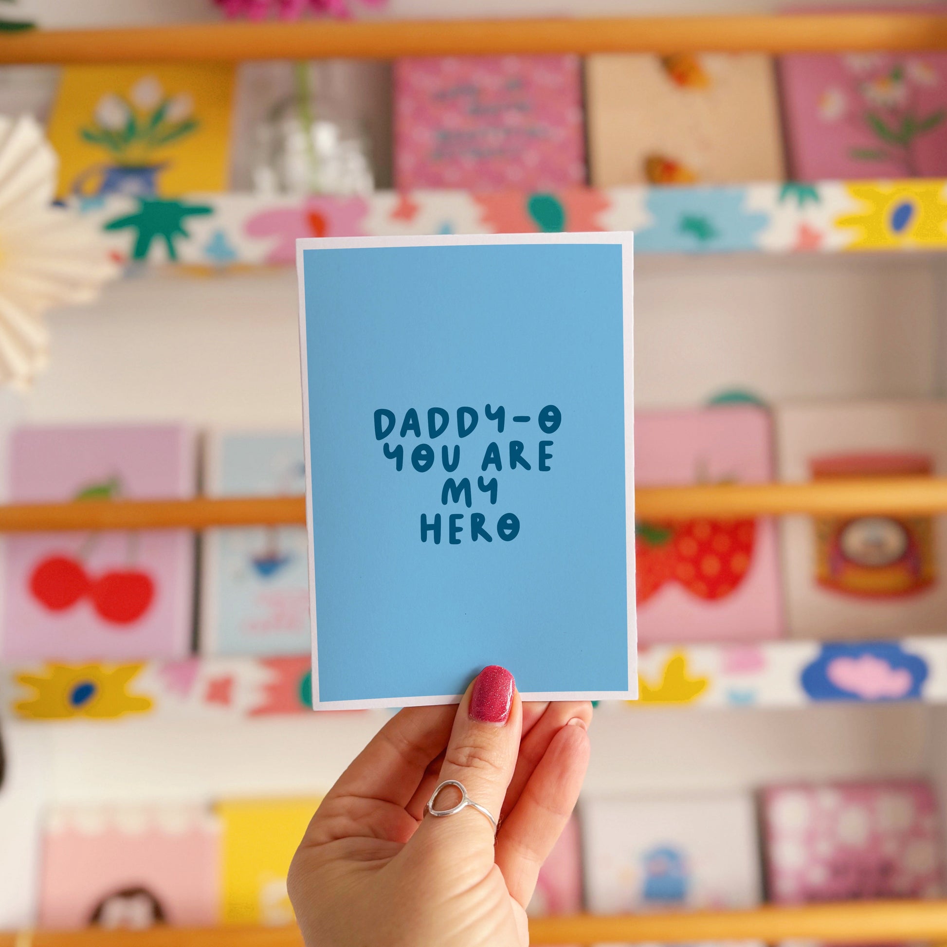 A blue greeting card with text that reads 'daddy-o you are my hero'.