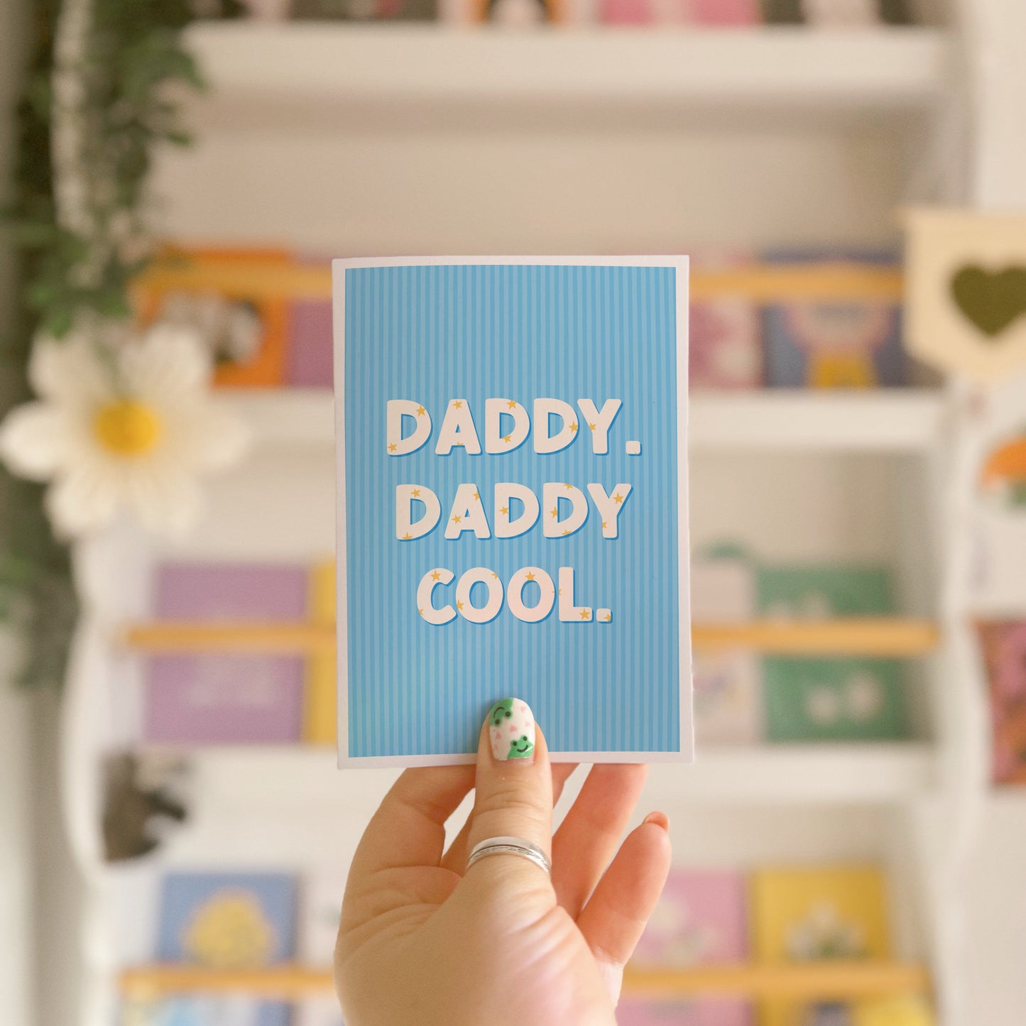 A blue greeting card with text that reads 'Daddy. Daddy Cool.' on the front with stars inside of the letters.