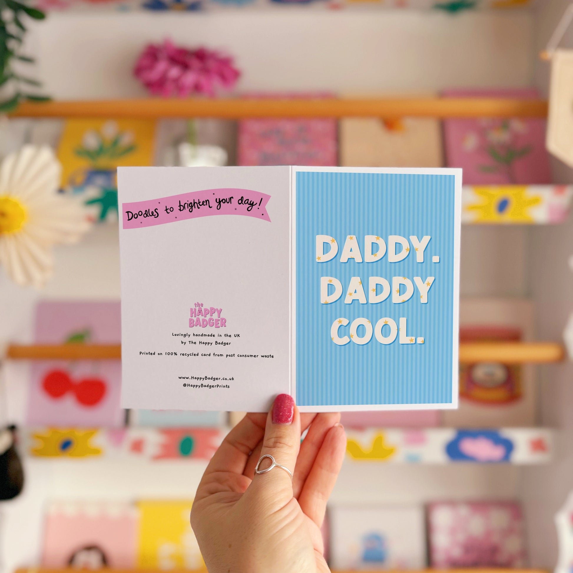A blue greeting card with text that reads 'Daddy. Daddy Cool.' on the front with stars inside of the letters.