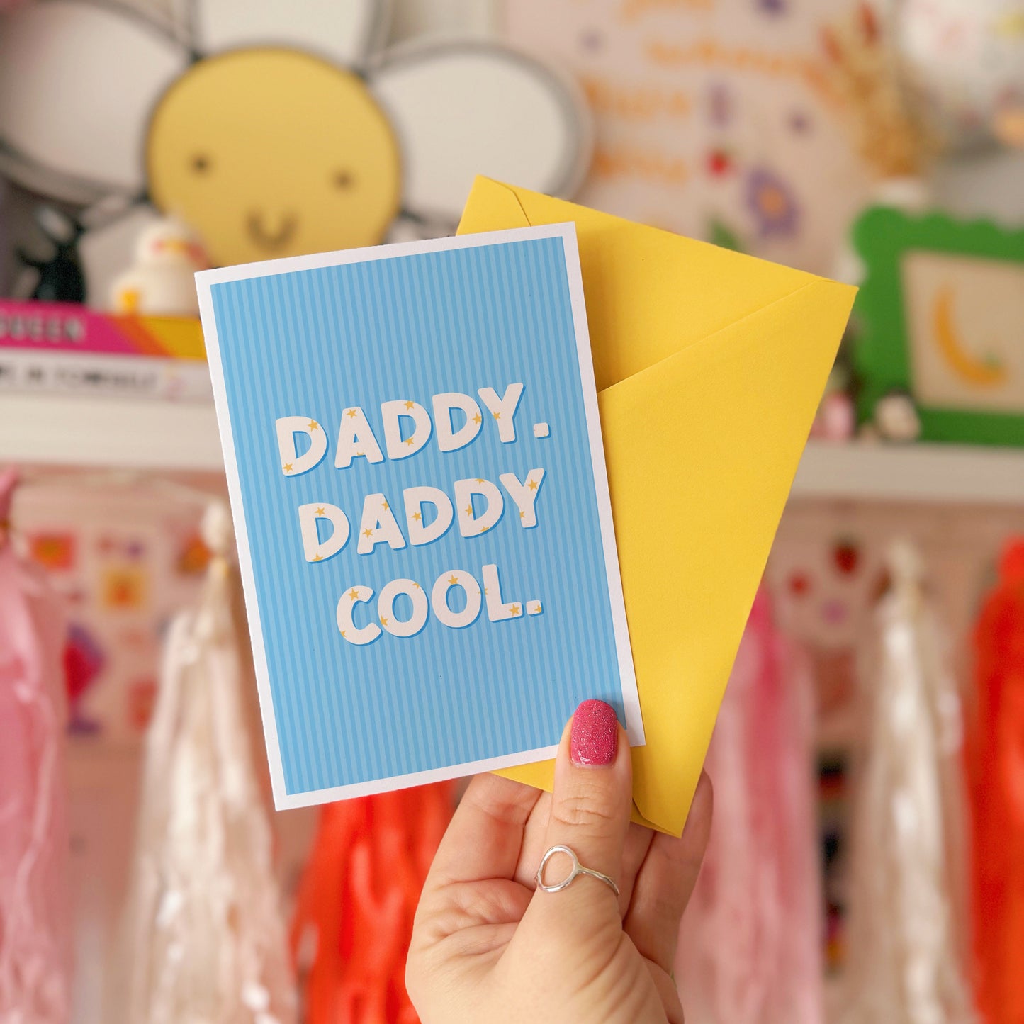 A blue greeting card with text that reads 'Daddy. Daddy Cool.' on the front with stars inside of the letters.