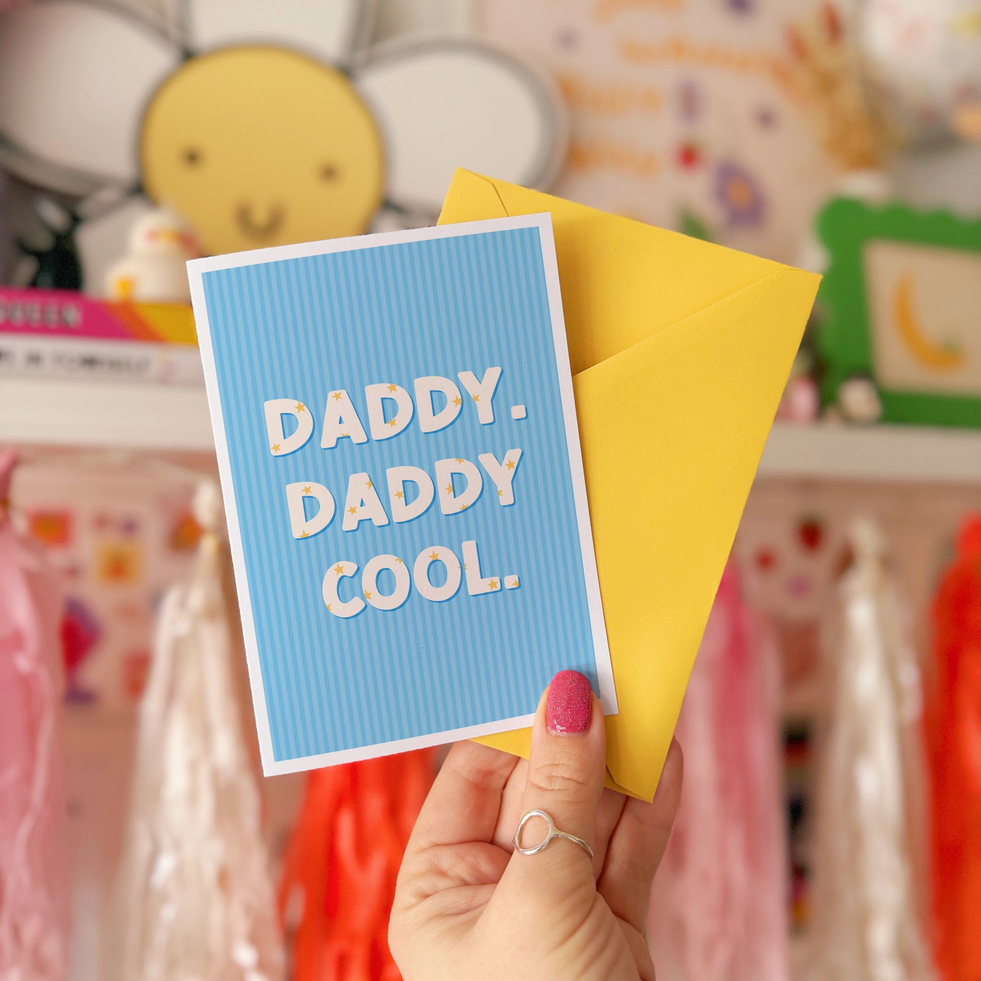 A blue greeting card with text that reads 'Daddy. Daddy Cool.' on the front with stars inside of the letters.