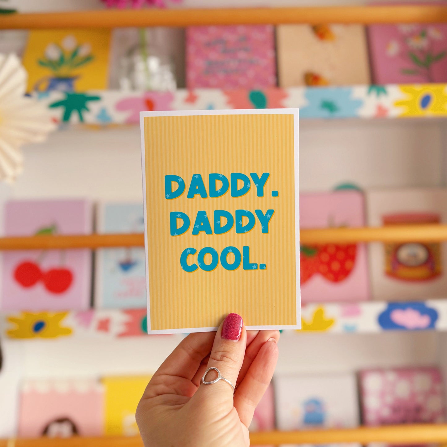 A yellow striped card, with bold blue text that reads 'Daddy. Daddy Cool.'