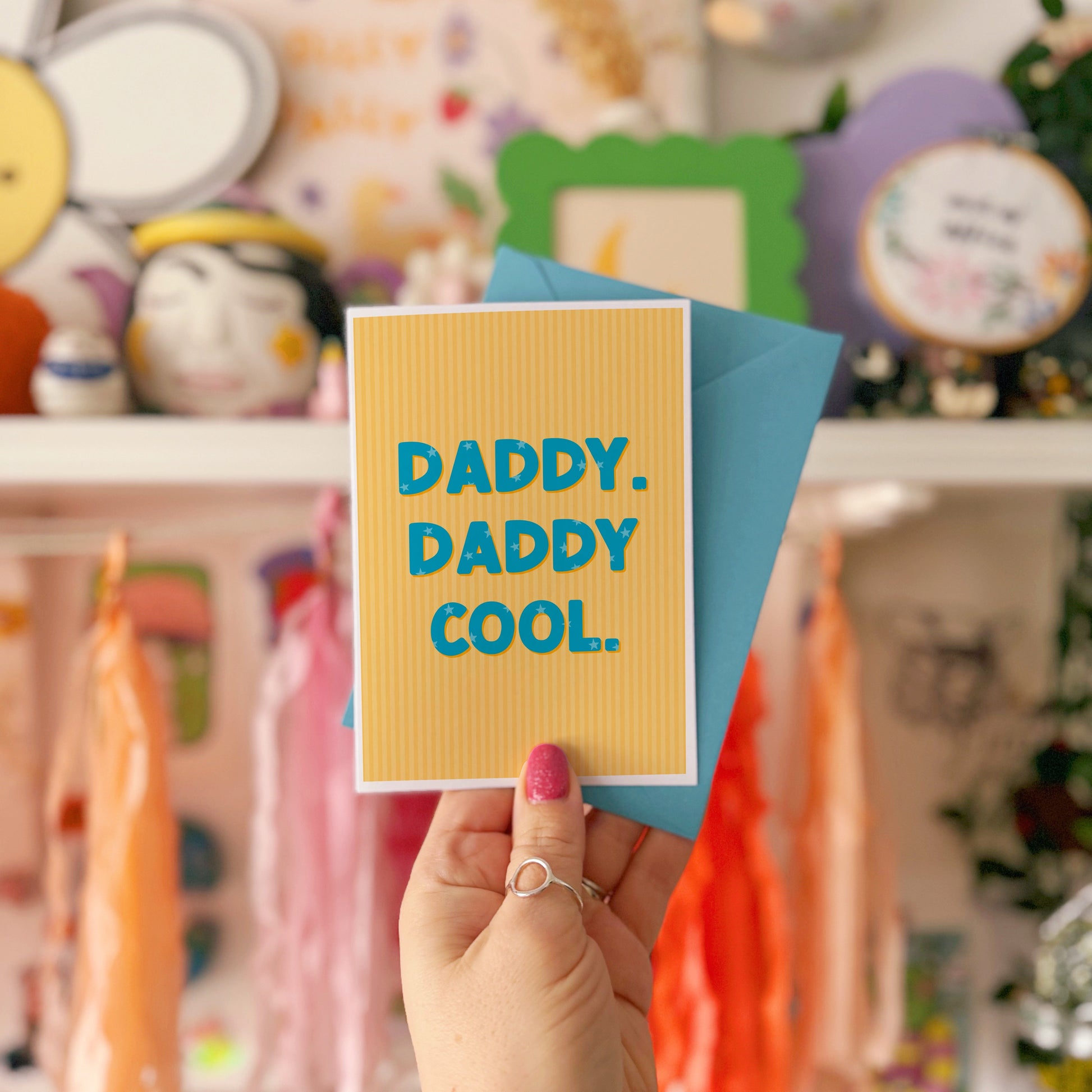 A yellow striped card, with bold blue text that reads 'Daddy. Daddy Cool.'