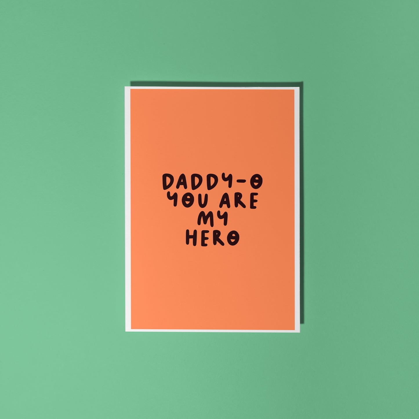 An orange greeting card with text in dark brown that says 'daddy-o you are my hero'.