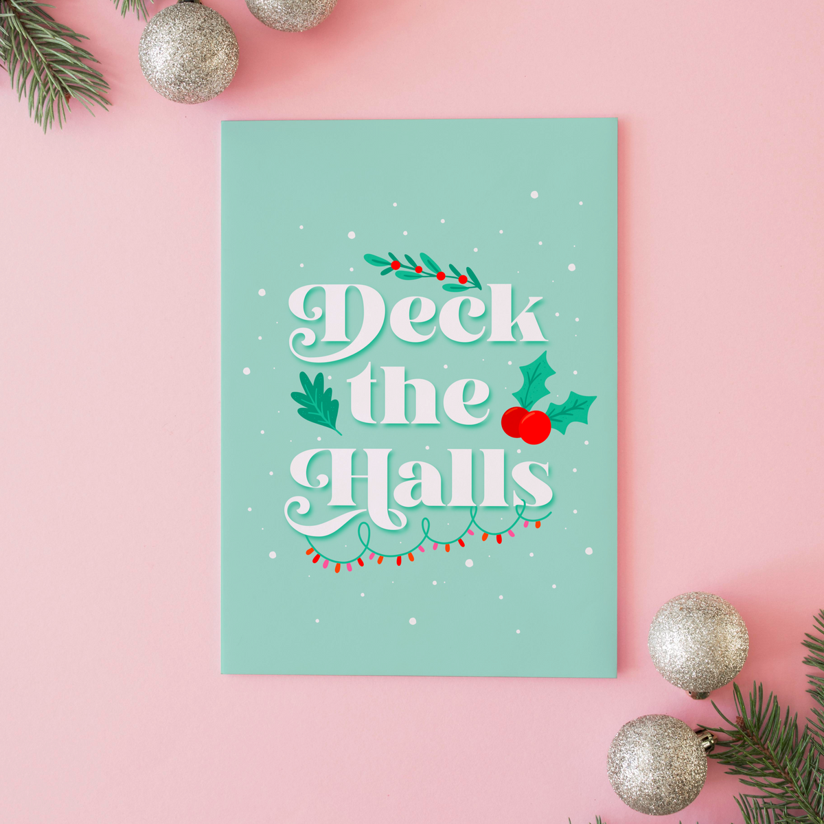A pale green Christmas quote print, featuring the words 'deck the halls', surrounded by little Christmas themed doodles.