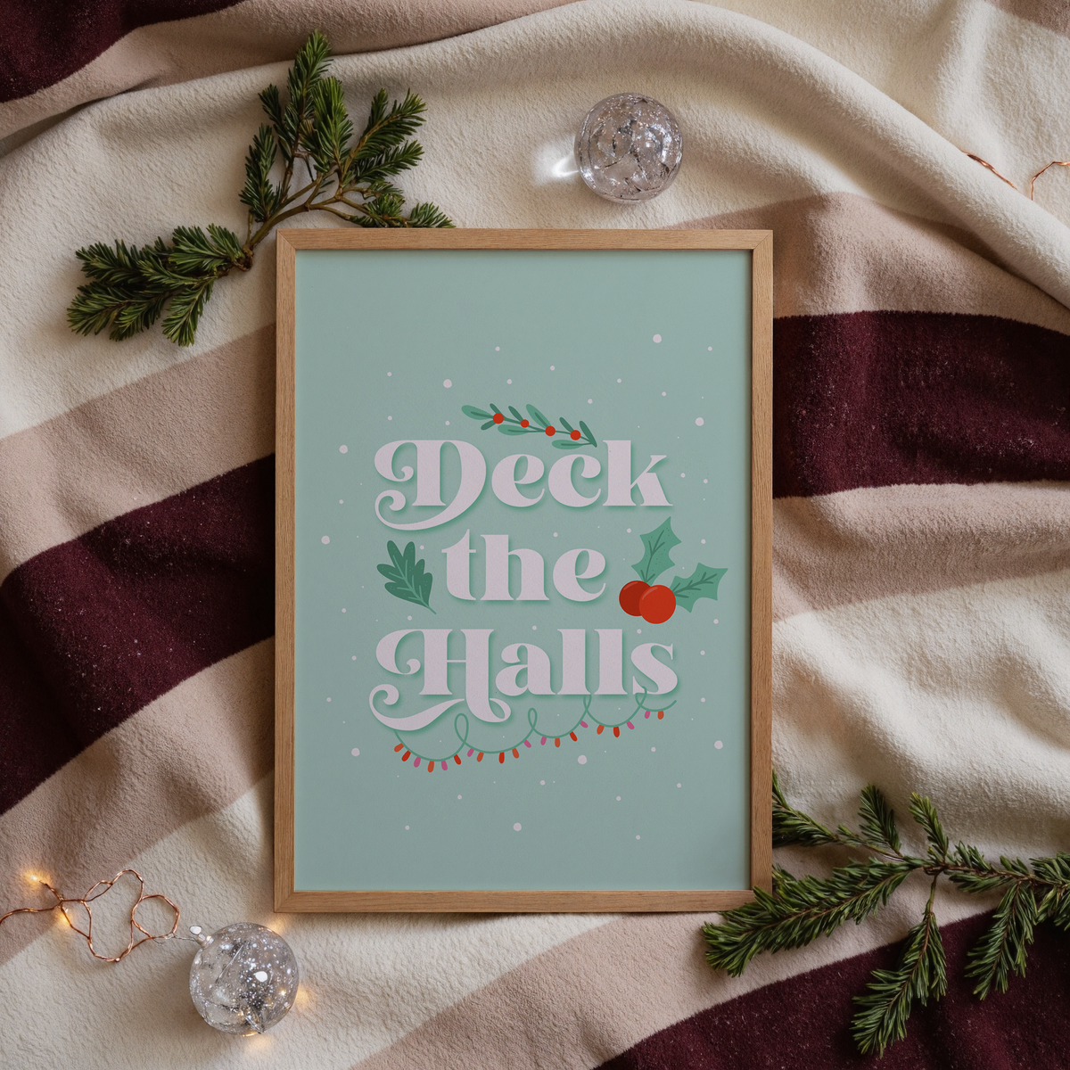 A pale green Christmas quote print, featuring the words 'deck the halls', surrounded by little Christmas themed doodles.