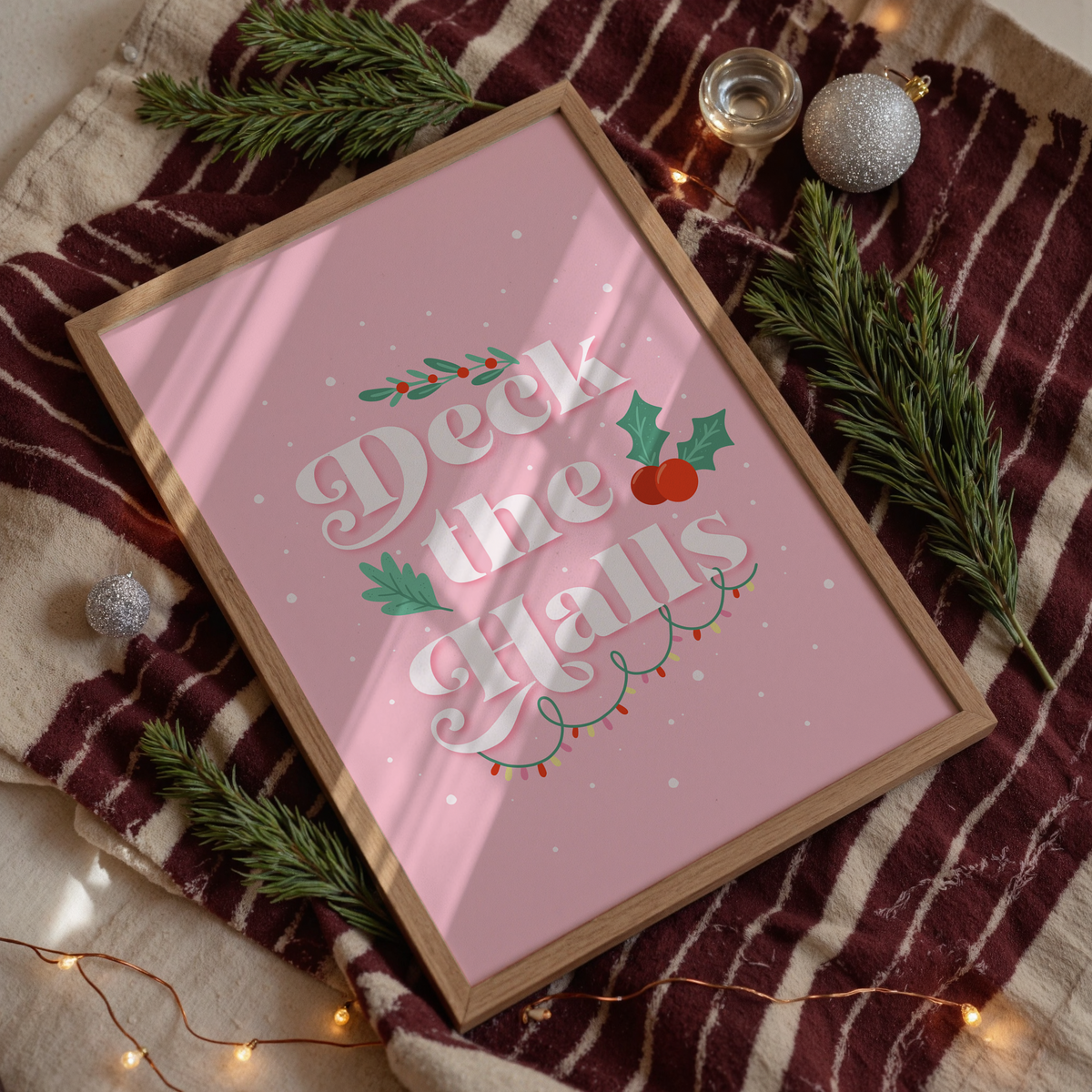 A pale pink Christmas quote print, featuring the words 'deck the halls', surrounded by little Christmas themed doodles.