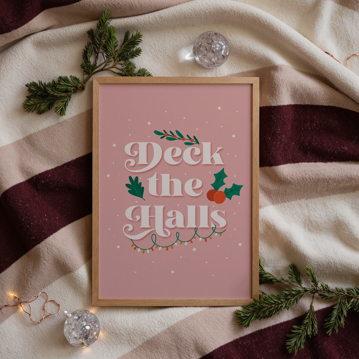 A warm pink Christmas quote print, featuring the words 'deck the halls', surrounded by little Christmas themed doodles.