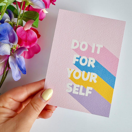 a motivational quote postcard, with the words do it for yourself on the front. the background of the postcard is pink with soft blue yellow and purple hues behind the text.