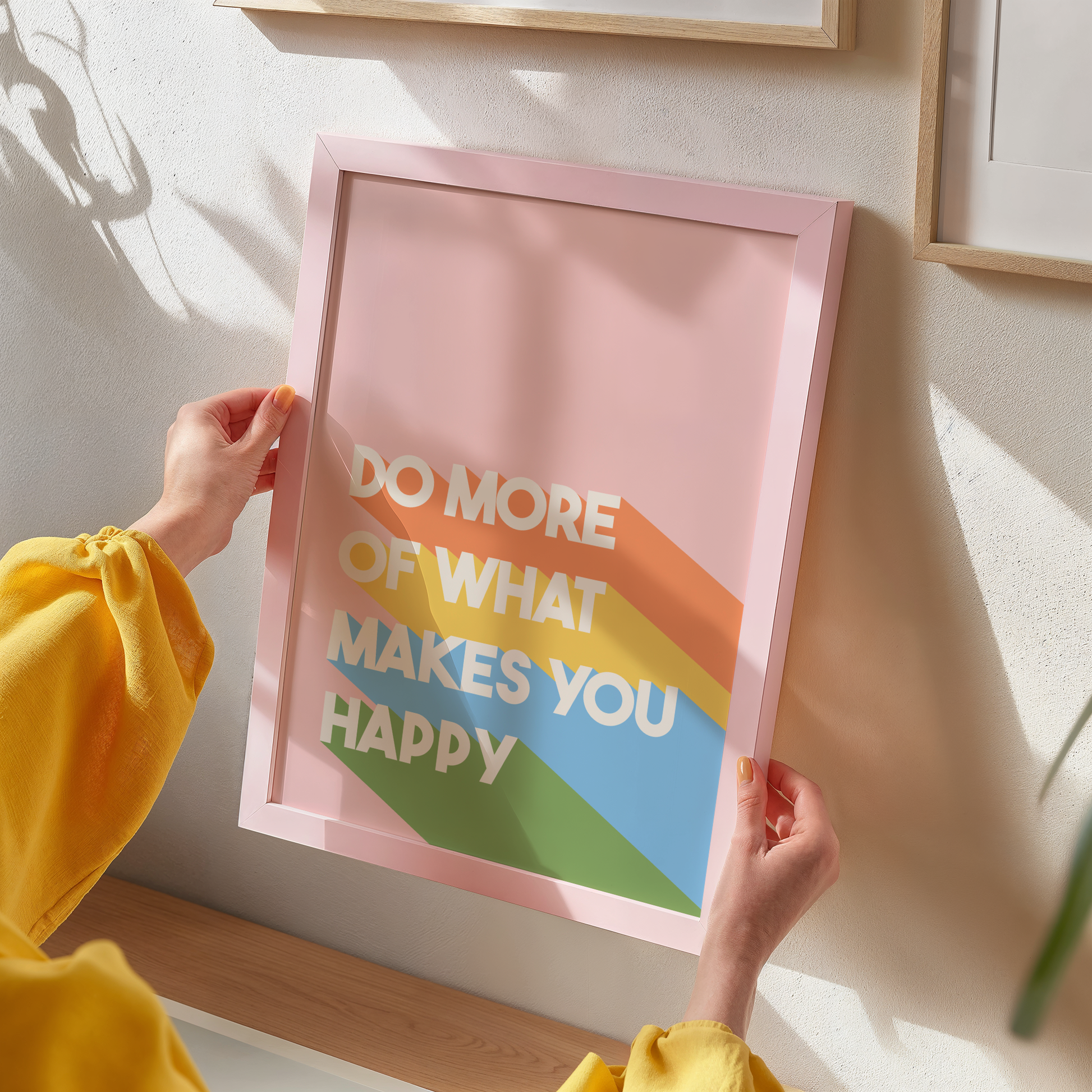A pinky orange print with the words 'do more of what makes you happy' on, with brightly coloured stripes.