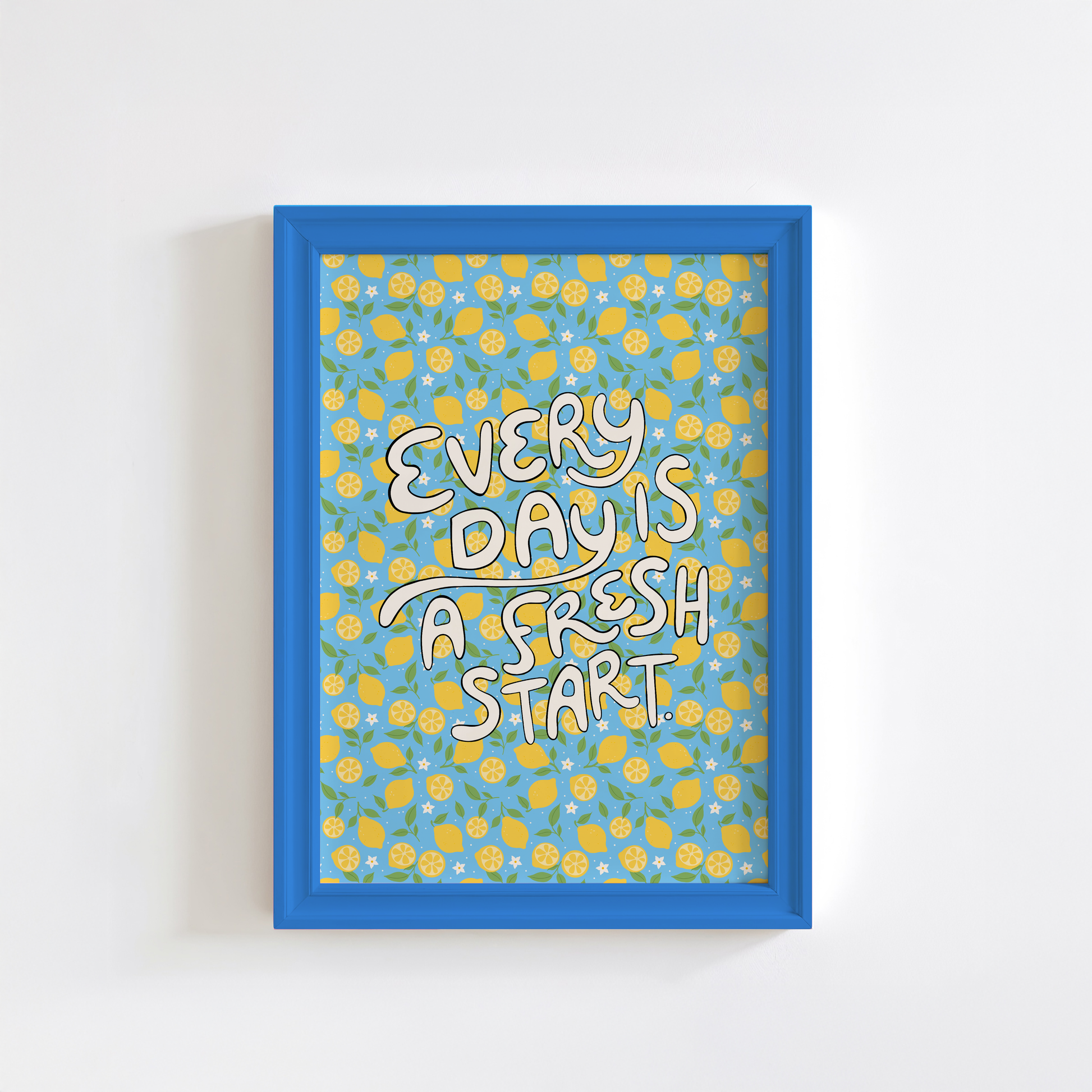 A bright quote print, with hand lettered words reading 'every day is a fresh start' on a blue background with a lemon pattern.