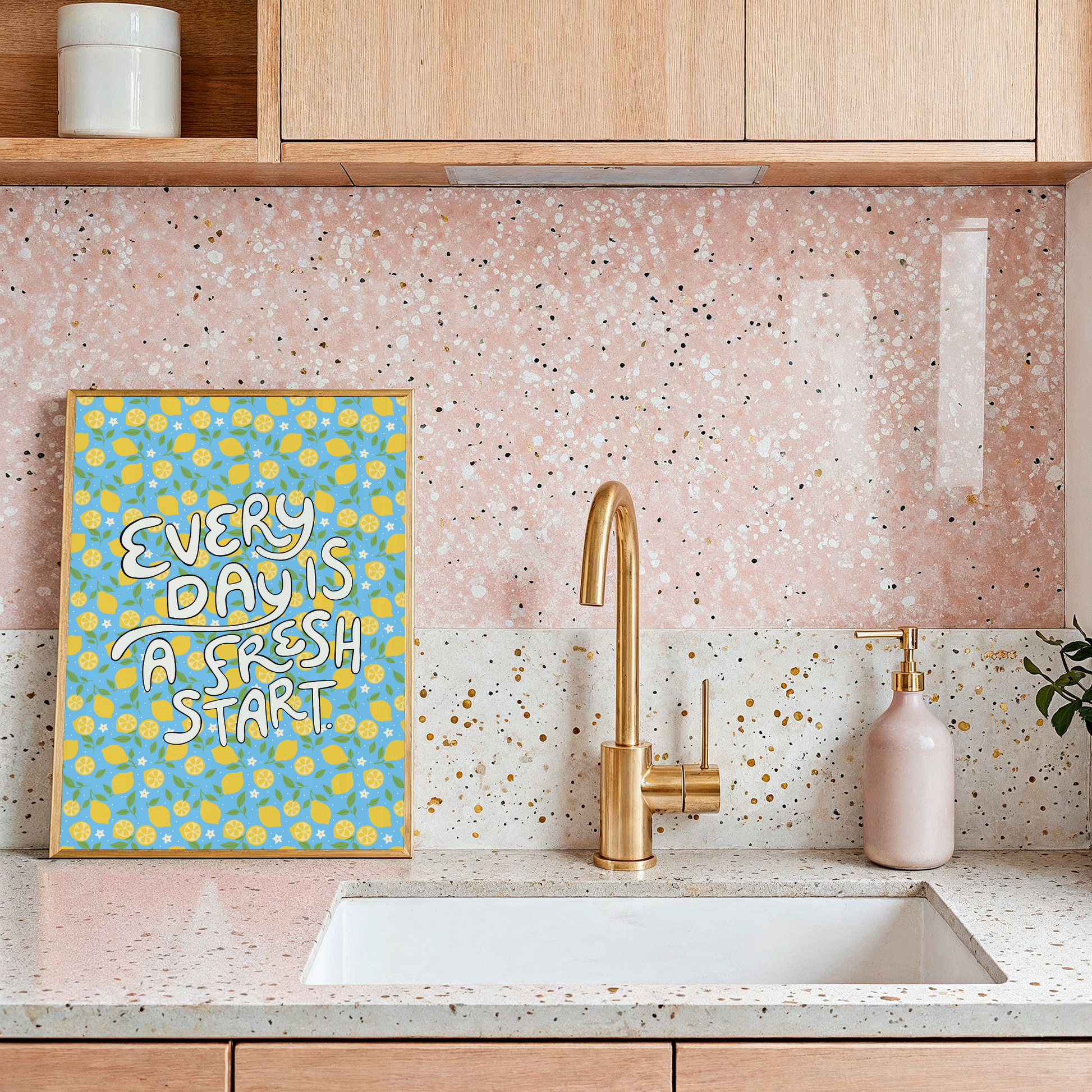 A bright quote print, with hand lettered words reading 'every day is a fresh start' on a blue background with a lemon pattern.