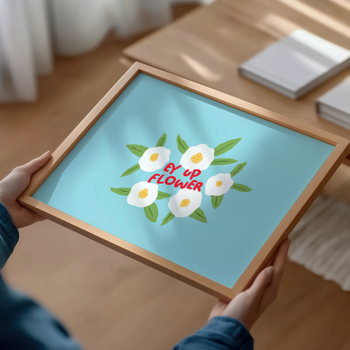 A blue print with illustrations of white flowers surrounding a quote, in red text, that says 'Ey Up Flower'. The print is horizontal orientation.