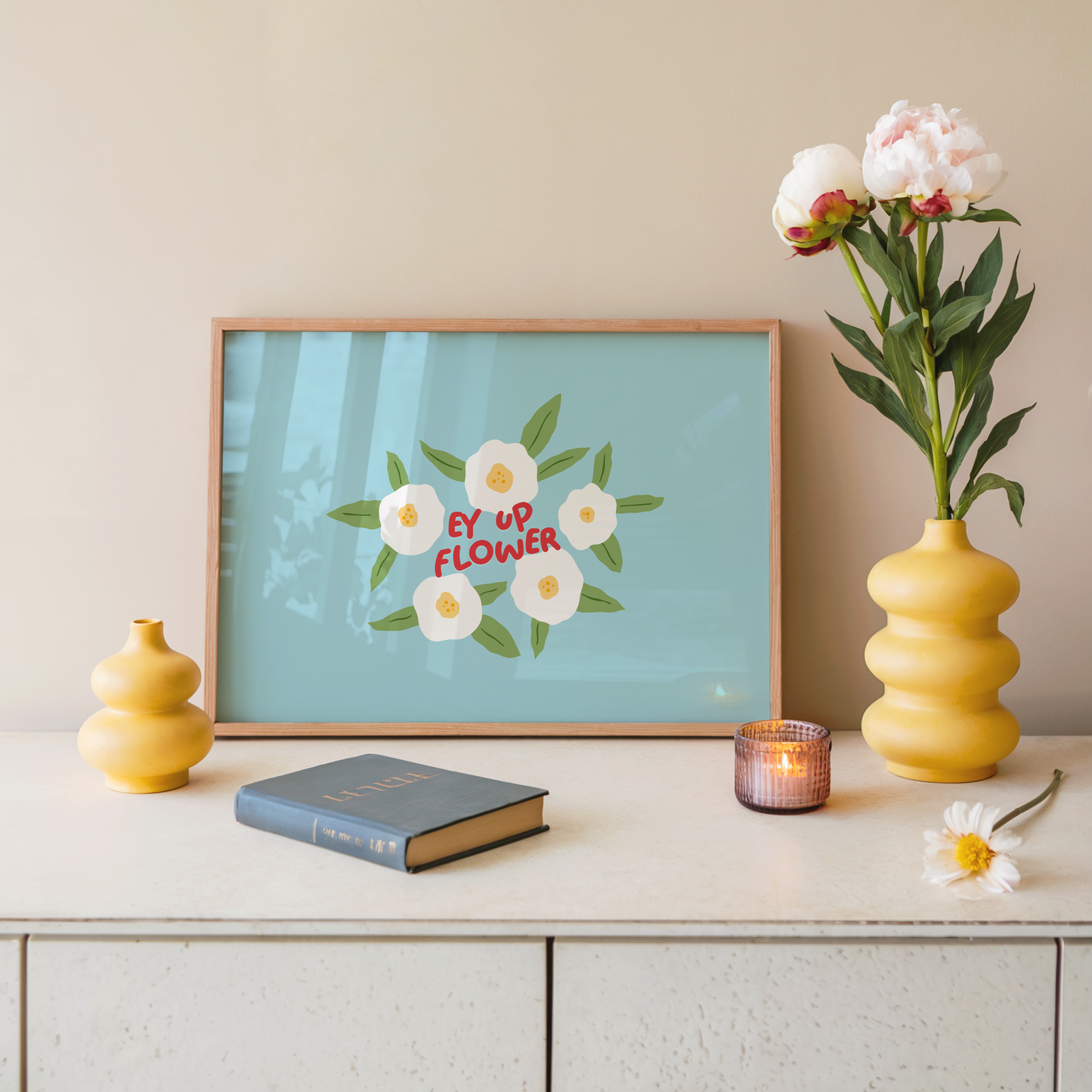 A blue print with illustrations of white flowers surrounding a quote, in red text, that says 'Ey Up Flower'. The print is horizontal orientation.