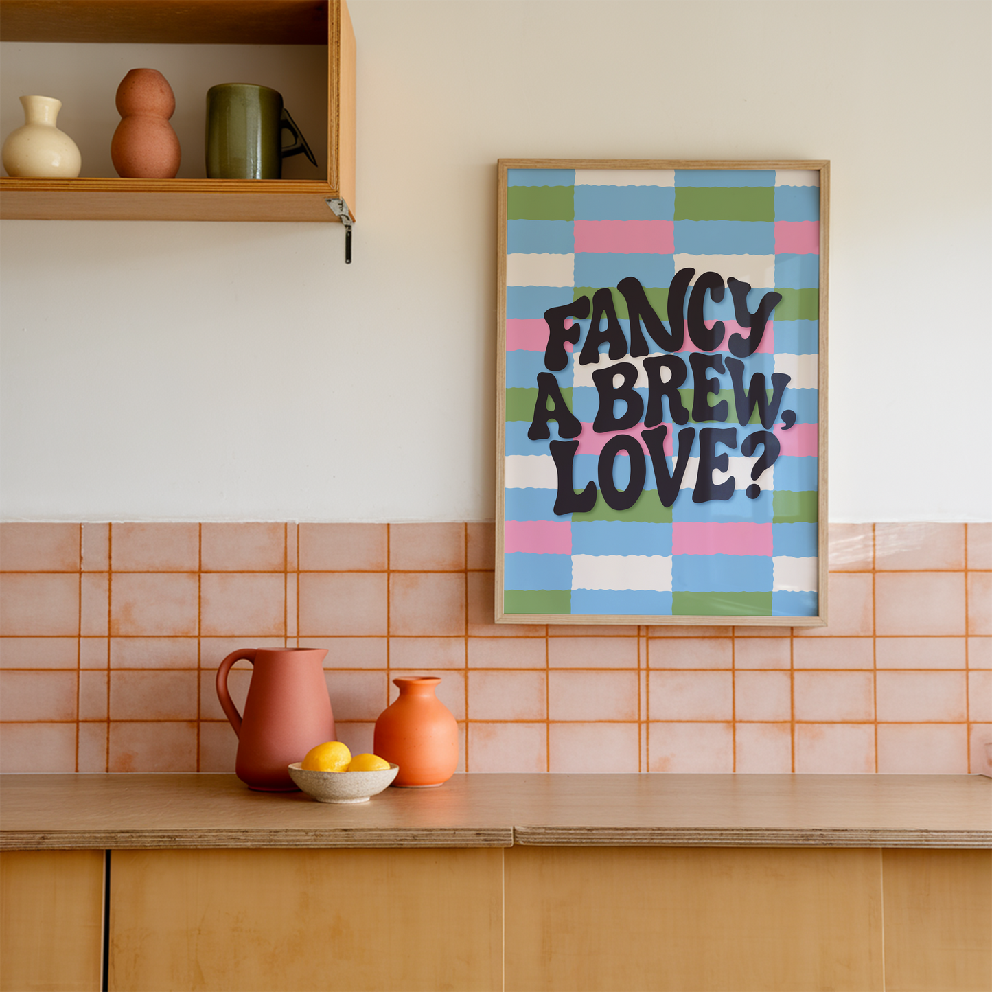 A brightly coloured print with a pink, blue, green and cream checkerboard pattern. In the centre of the print is a quote that reads 'fancy a brew, love?'.