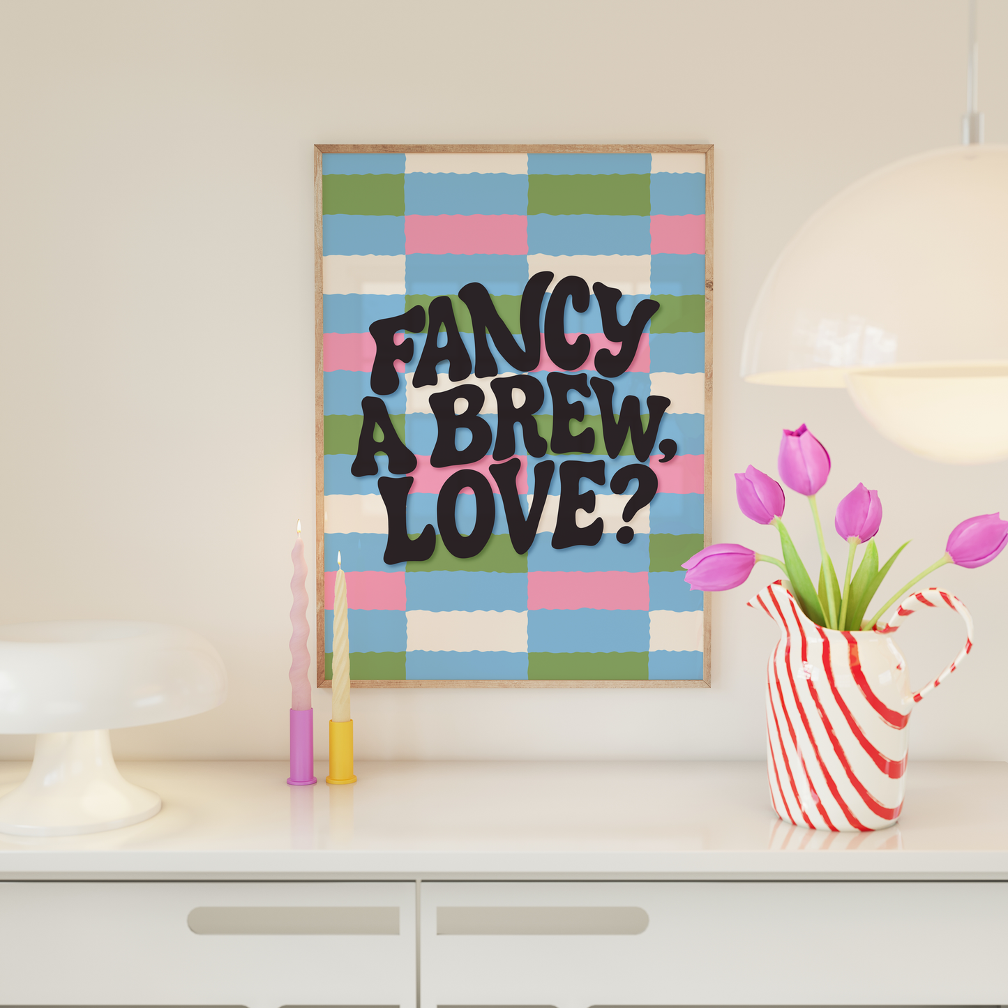 A brightly coloured print with a pink, blue, green and cream checkerboard pattern. In the centre of the print is a quote that reads 'fancy a brew, love?'.