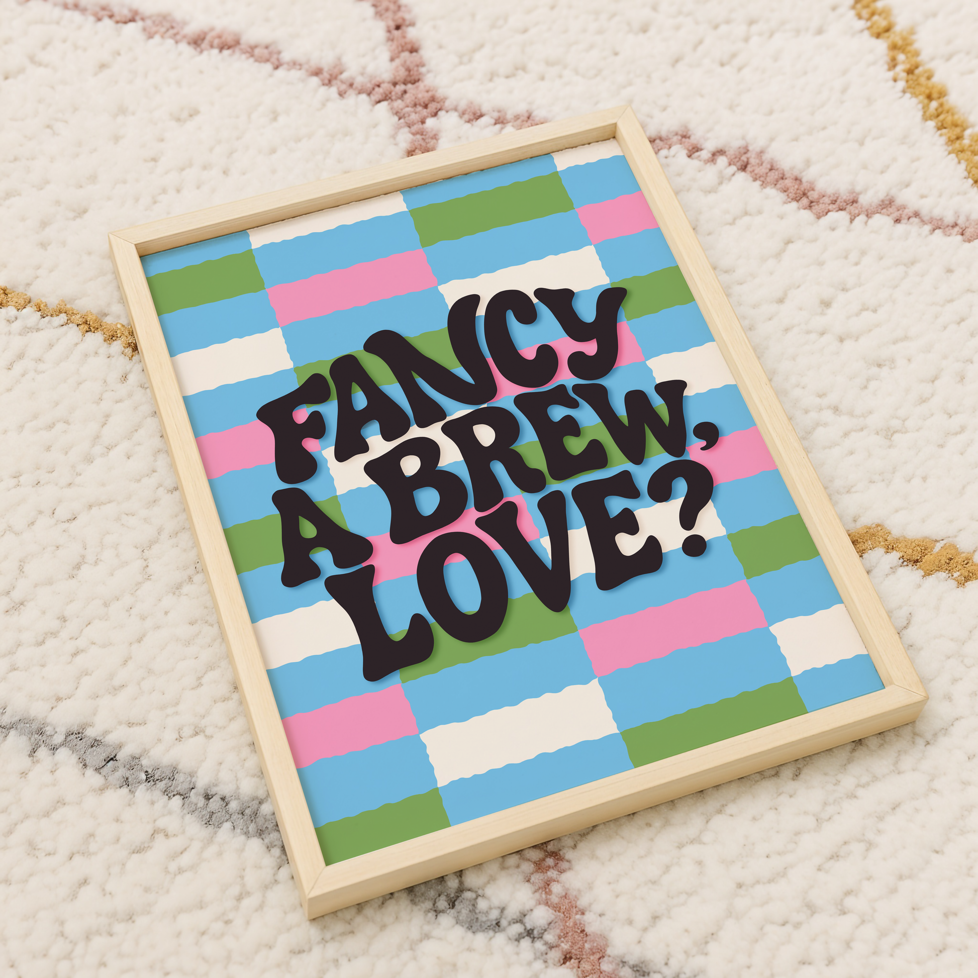 A brightly coloured print with a pink, blue, green and cream checkerboard pattern. In the centre of the print is a quote that reads 'fancy a brew, love?'.
