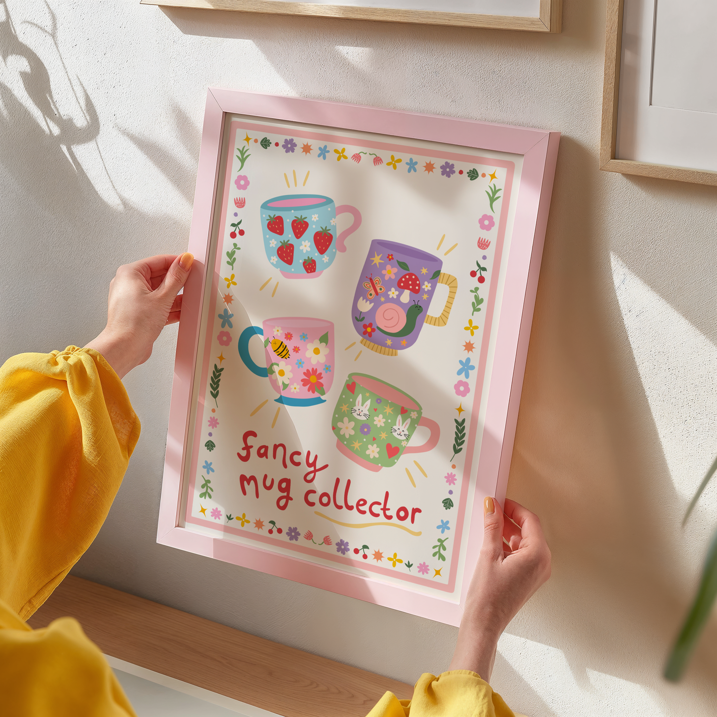 An illustrated print with four decorative mugs, and a quote underneath that reads 'fancy mug collector'. The print has a decorative border of flowers and doodles.
