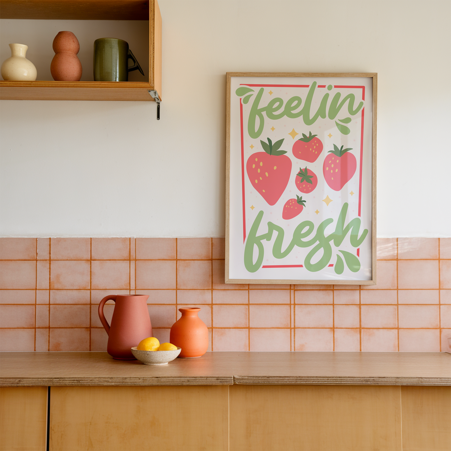 A colourful art print with the phrase 'feelin' fresh' surrounded by illustrations of strawberries, shown in a frame.