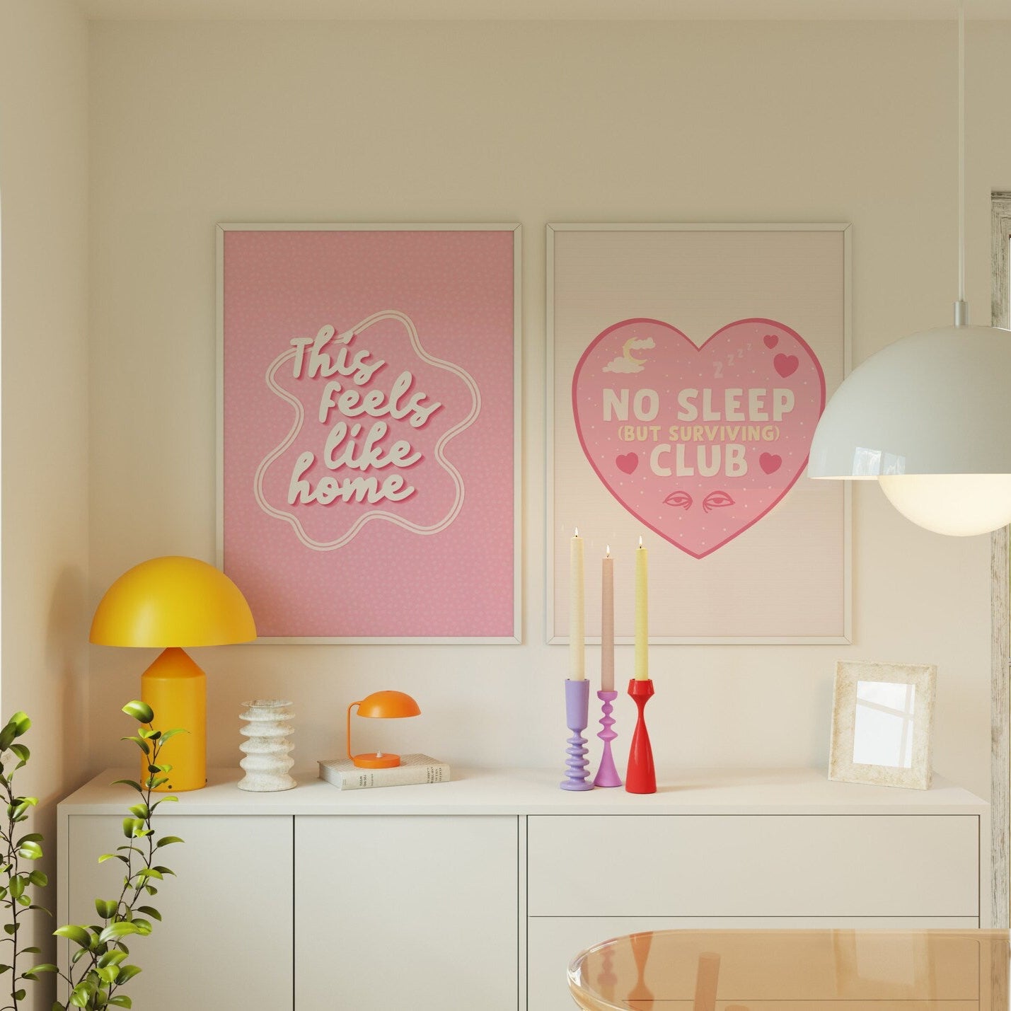 Two prints, one with a print with a pink heart, with the words 'No Sleep (but surviving) club' in the centre, with small sleep related doodles around the text. The other is a pink print, with the words ' this feels like home' in the centre.