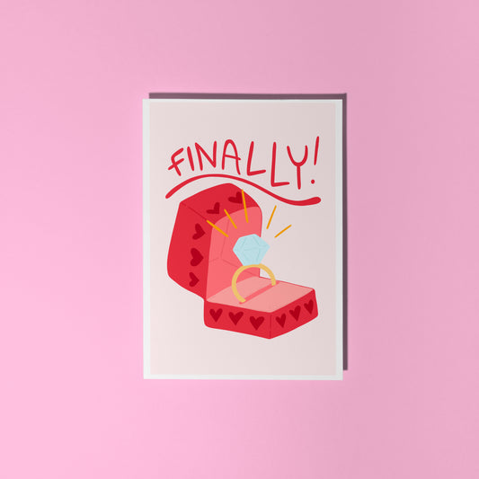 Card with a red engagement ring box and the word 'FINALLY!' on a light pink background.