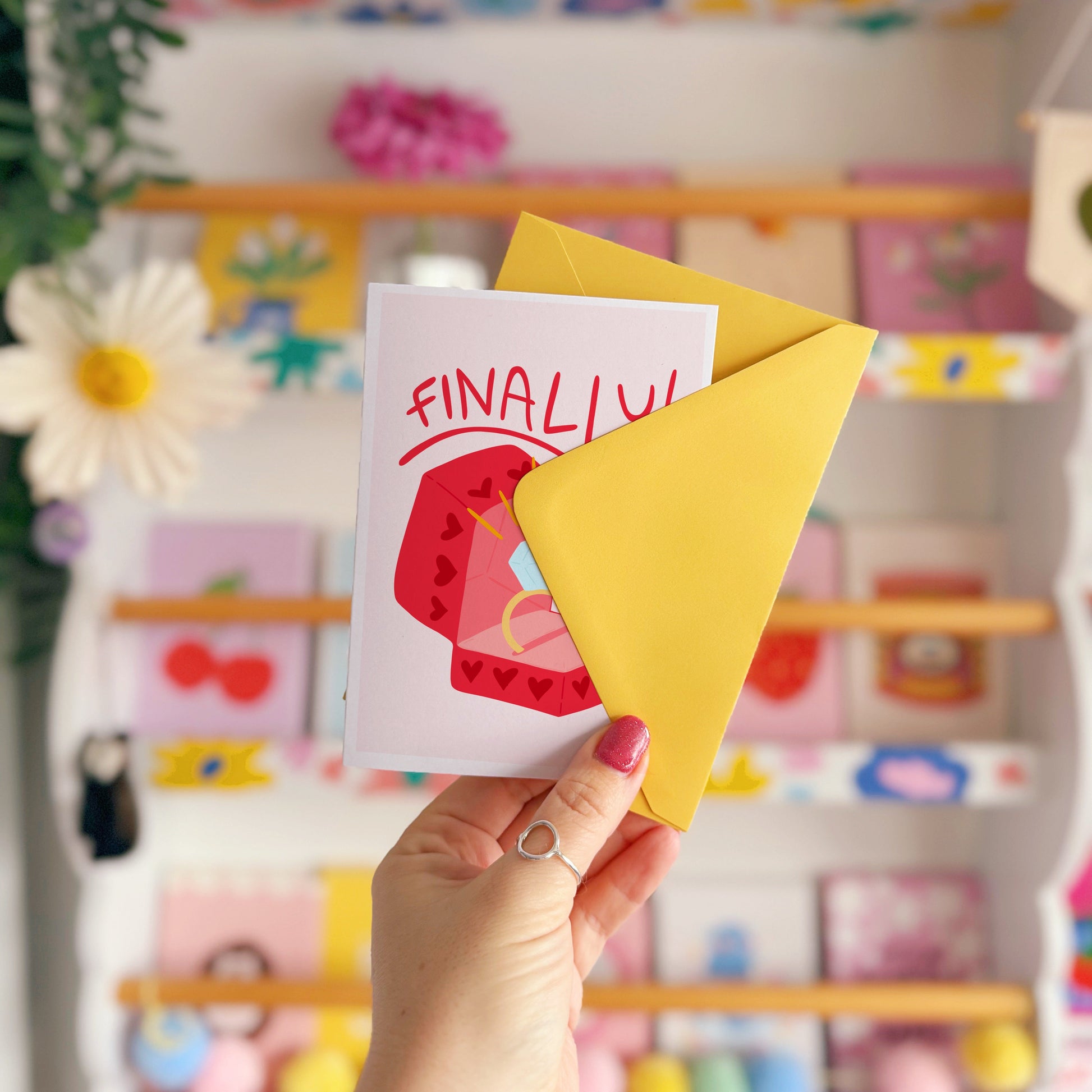 Card with a red engagement ring box and the word 'FINALLY!' on a light pink background.