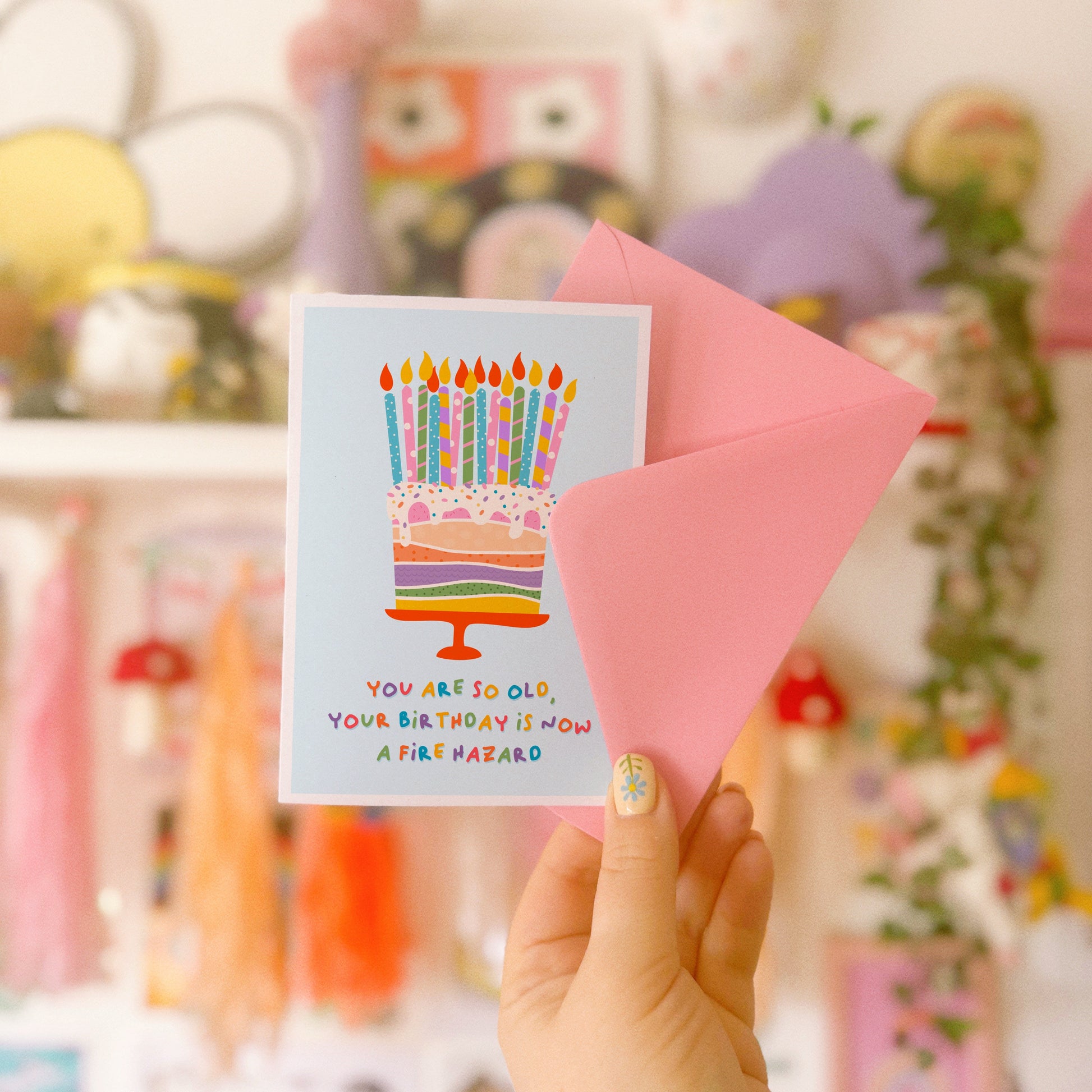 A birthday card with an illustration of a cake, topped with several candles. The text underneath the illustration reads 'you are so old, your birthday is now a fire hazard'.