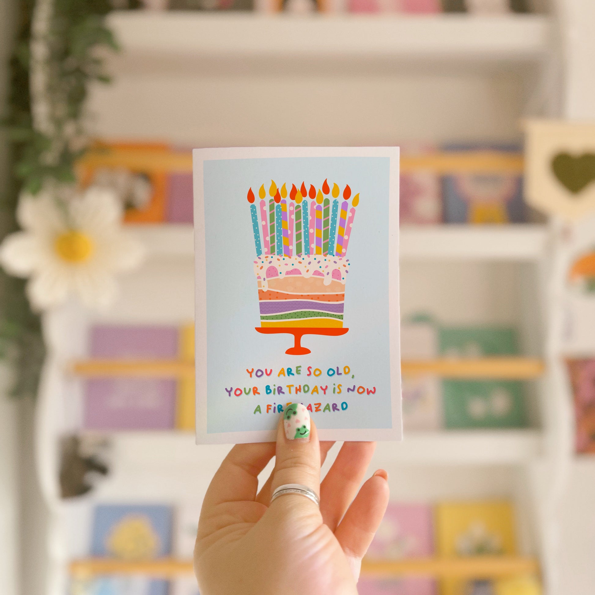 A birthday card with an illustration of a cake, topped with several candles. The text underneath the illustration reads 'you are so old, your birthday is now a fire hazard'.