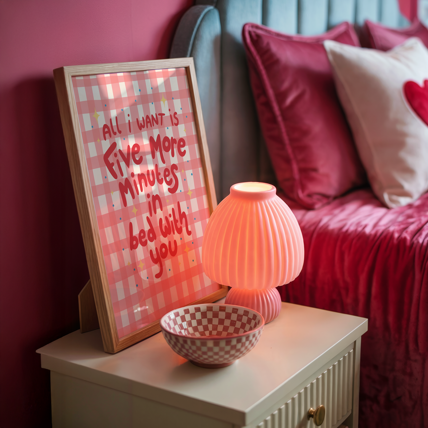 A pinky red checkered print with hand lettered text that says 'all I want is five more minutes in bed with you'.