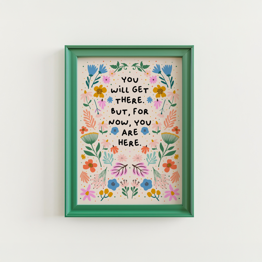 A floral illustration print, drawn in a symmetrical pattern with vibrant blues, oranges and greens and pinks - surrounding a quote in black handwriting that says you will get there. but for now, you are here.