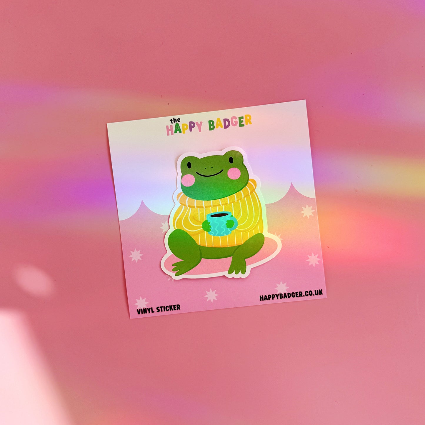 Vinyl sticker of a cartoon frog in a yellow sweater on a pink gradient background