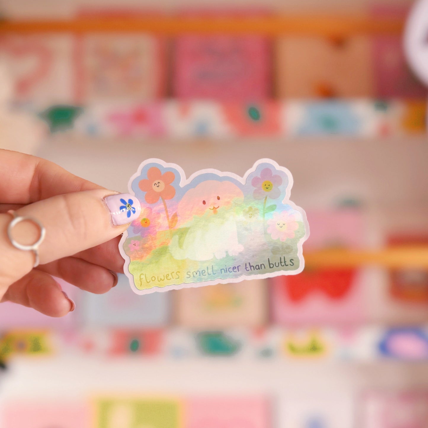 An illustrated sticker of a dog sat amongst flowers, with the quote 'flowers smell nicer than butts' underneath'.