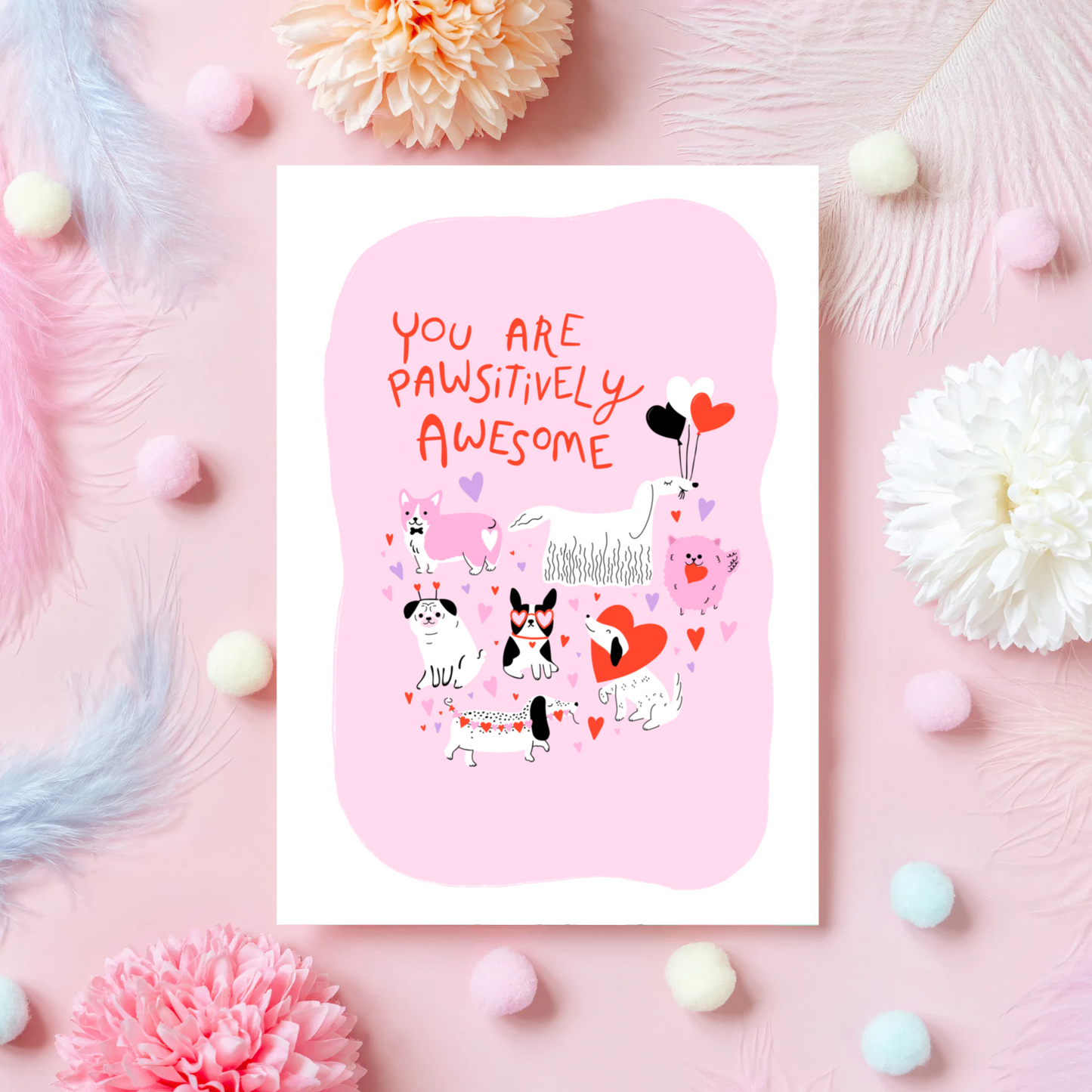 A greetings card for love and appreciation, showing 7 quirky dog illustrations surrounded by hearts and love themed elements. The text on the card is red and says 'You are pawsitively awesome'