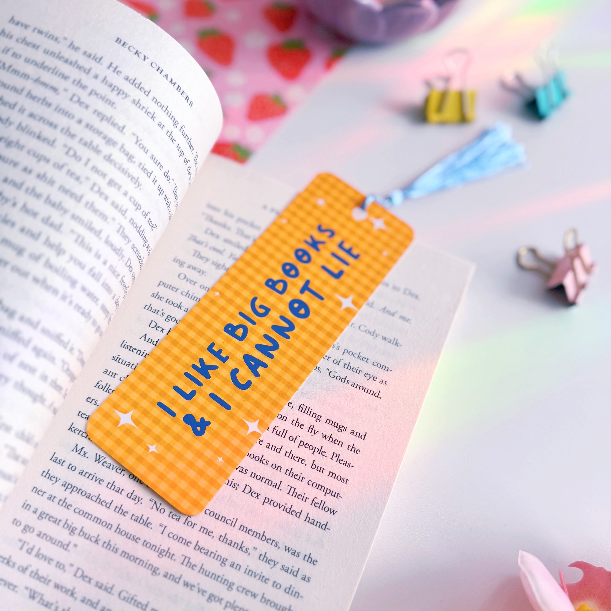 A yellow gingham bookmark with a blue tassel, and blue text that reads 'I like big books and I cannot lie' on the front side.