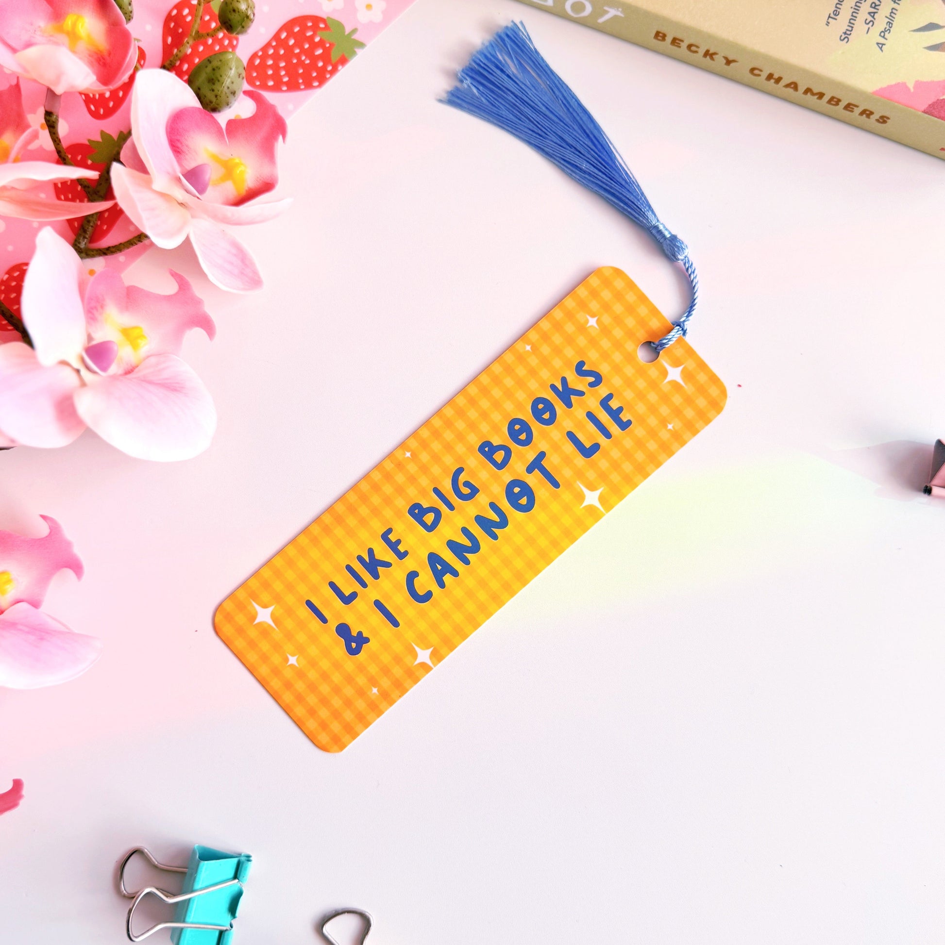 A yellow gingham bookmark with a blue tassel, and blue text that reads 'I like big books and I cannot lie' on the front side.