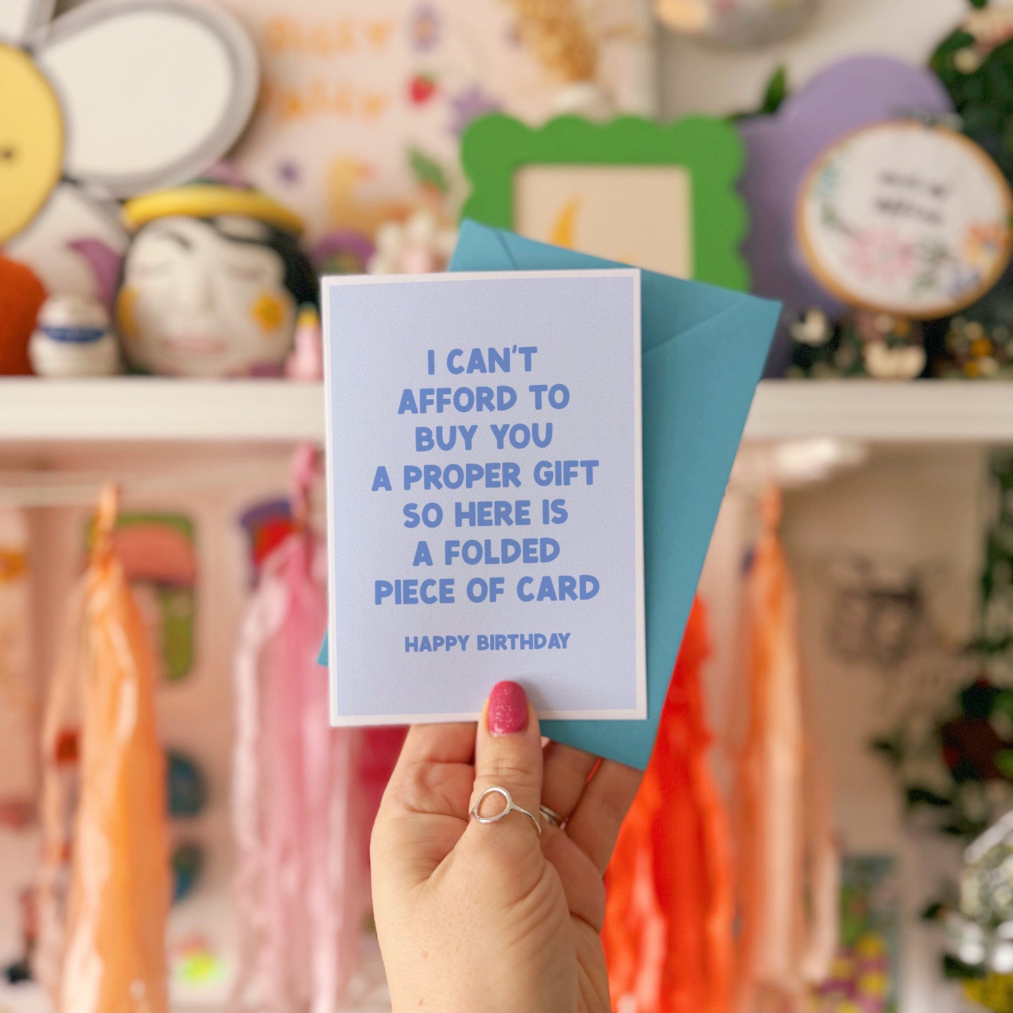 Person holding a card with humorous text in front of colorful decorations
