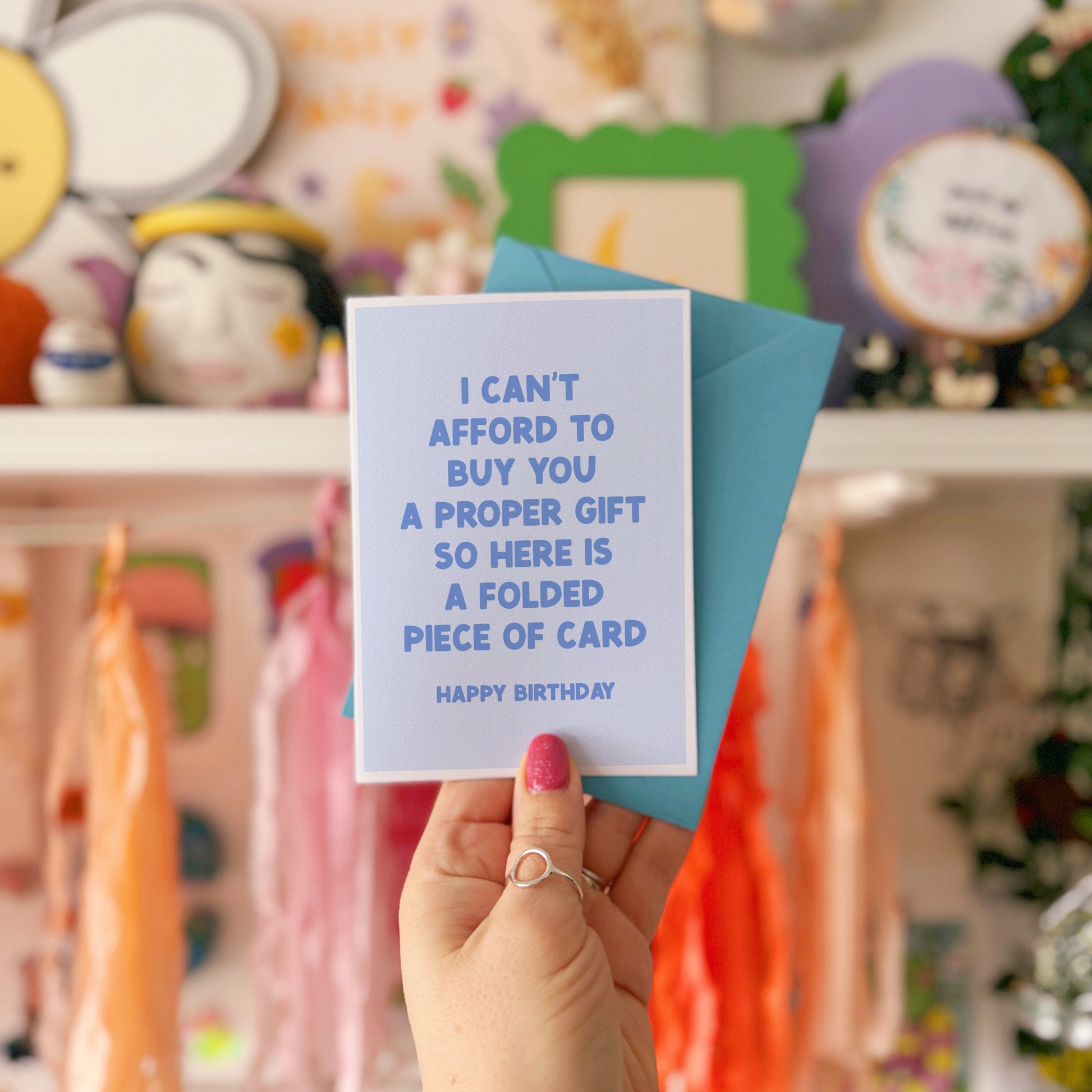 Person holding a card with humorous text in front of colorful decorations