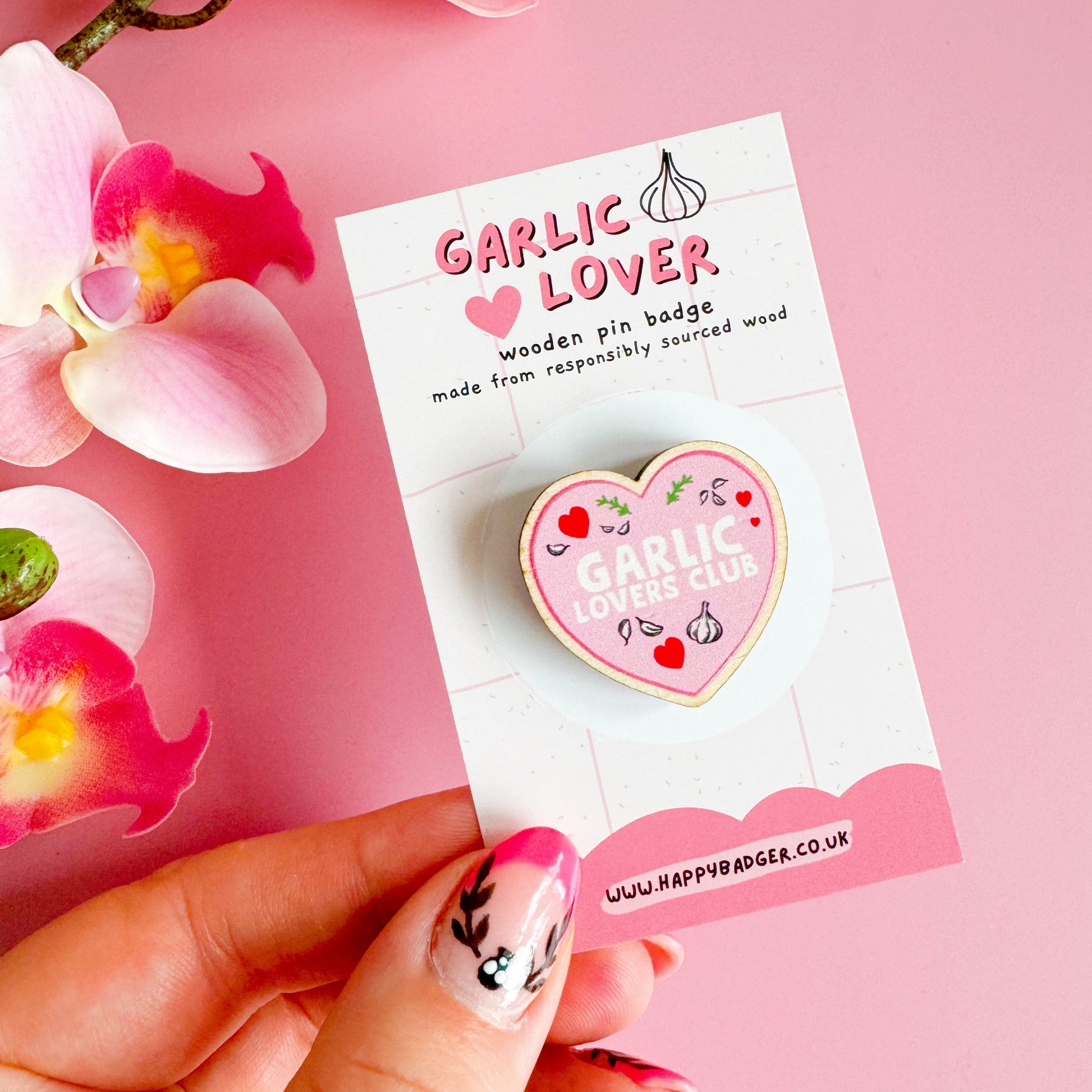 A wooden eco friendly pin badge of a pink heart with the words garlic lovers club inside of it.