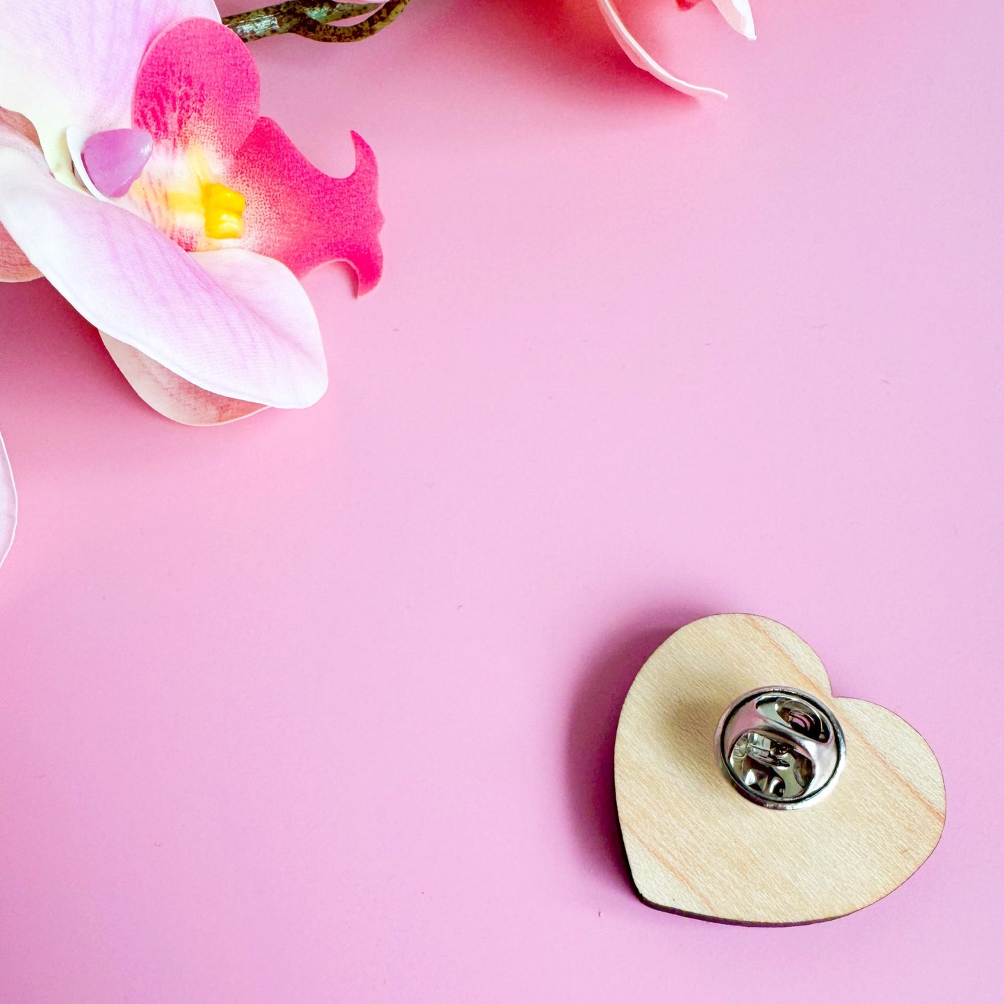 A wooden eco friendly pin badge of a pink heart with the words garlic lovers club inside of it.