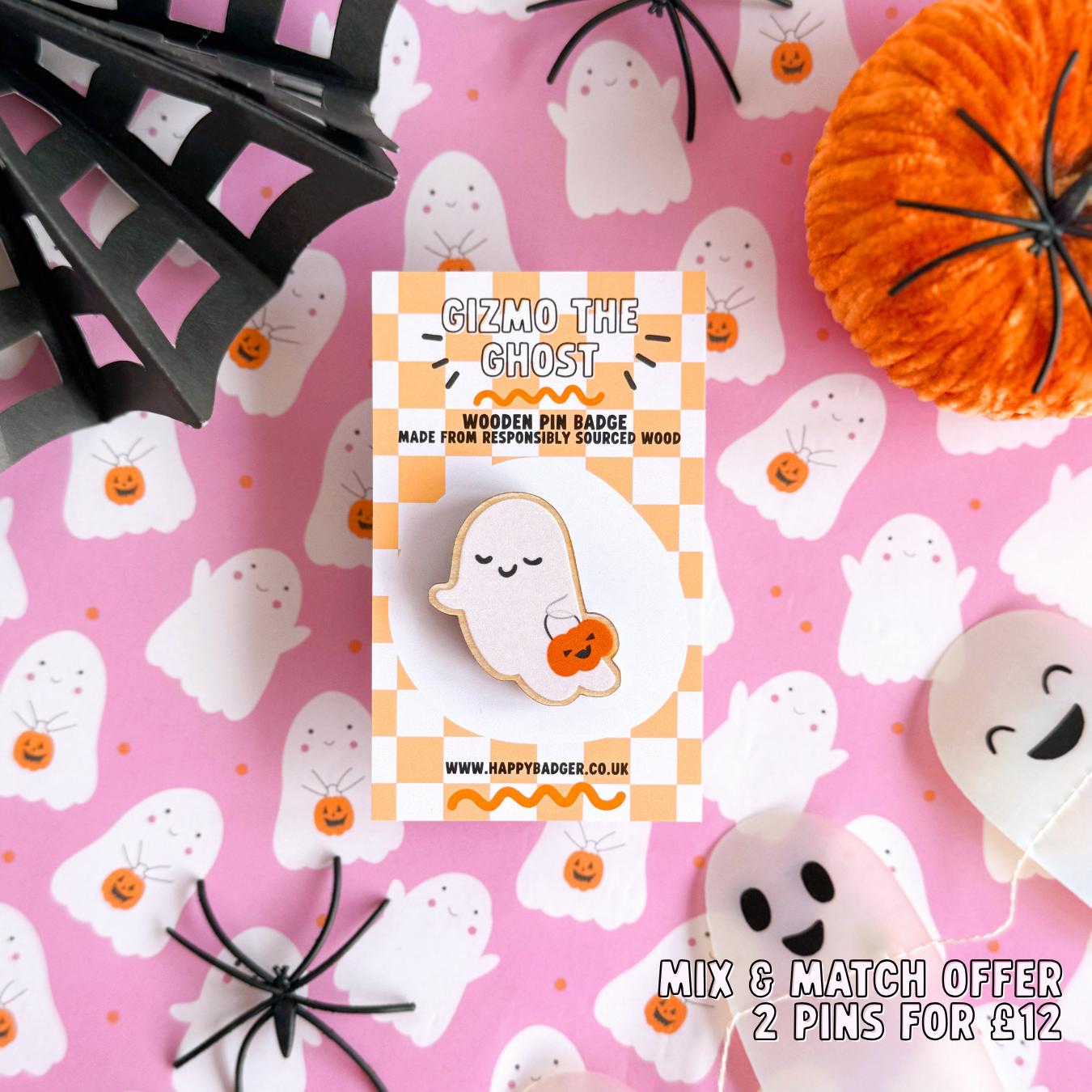 A wooden pin badge, of a cute smiling ghost, holding a trick or treating tub which is a pumpkin.