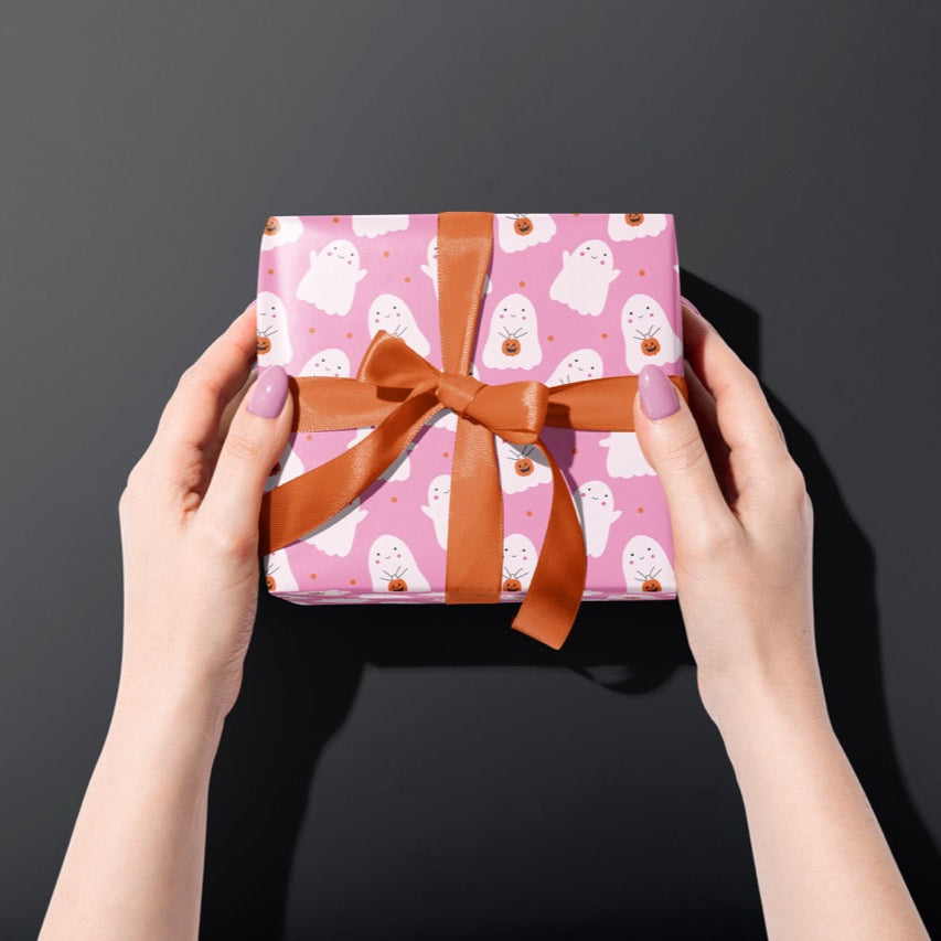 A gift wrapped present, wrapped up in bright pink ghost print gift wrap from The Happy Badger.