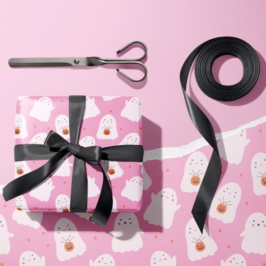 A gift wrapped present, wrapped up in bright pink ghost print gift wrap from The Happy Badger.