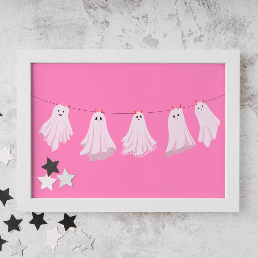 A pink Halloween print with five different ghosts made from bedsheets, hanging on a washing line.
