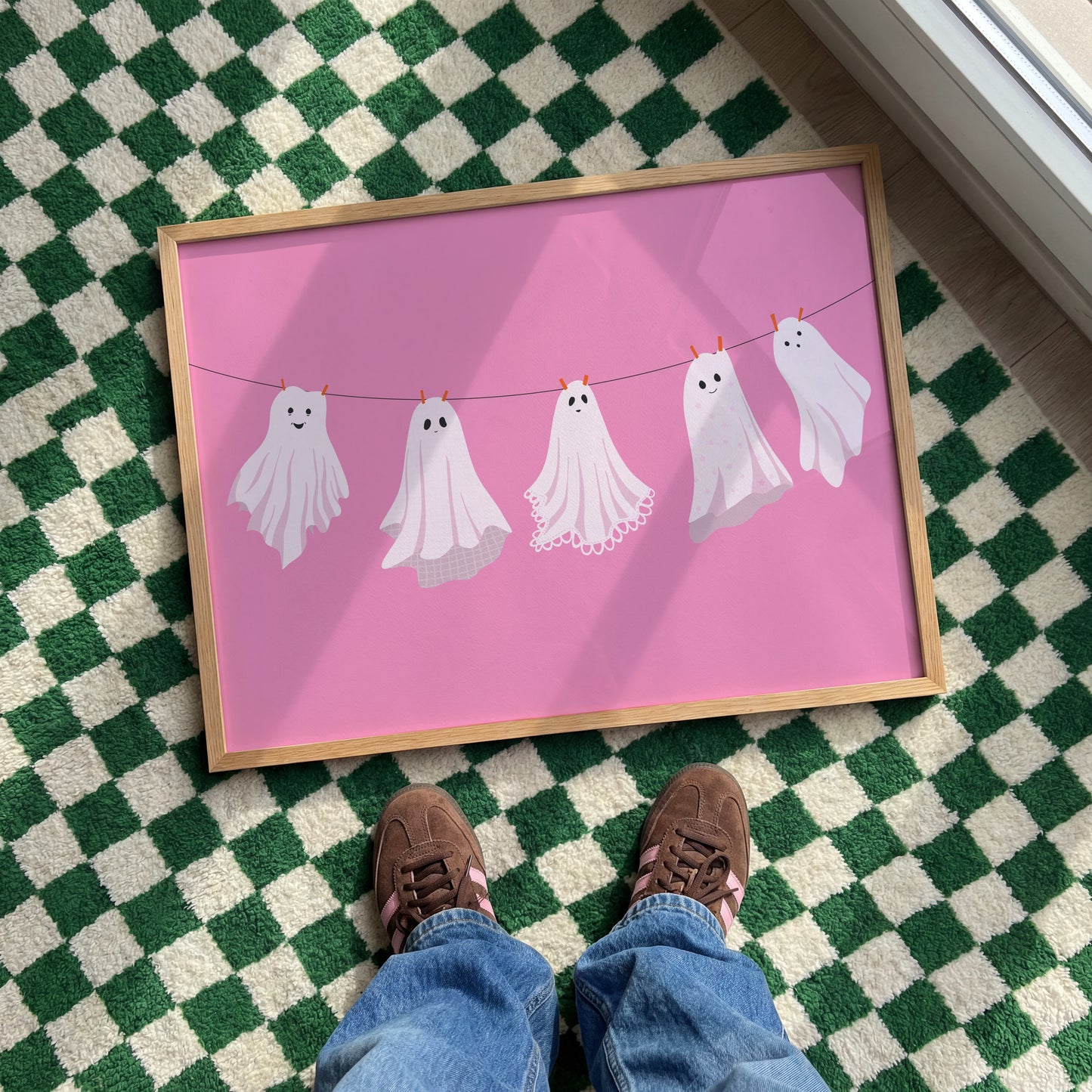 A pink Halloween print with five different ghosts made from bedsheets, hanging on a washing line.
