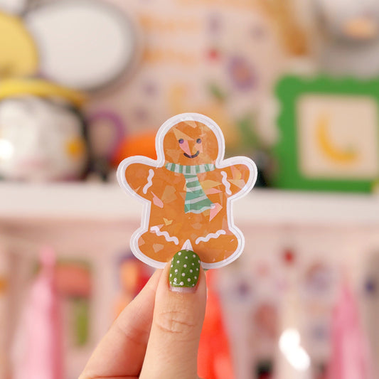 Hand holding a gingerbread man sticker with a blurred background
