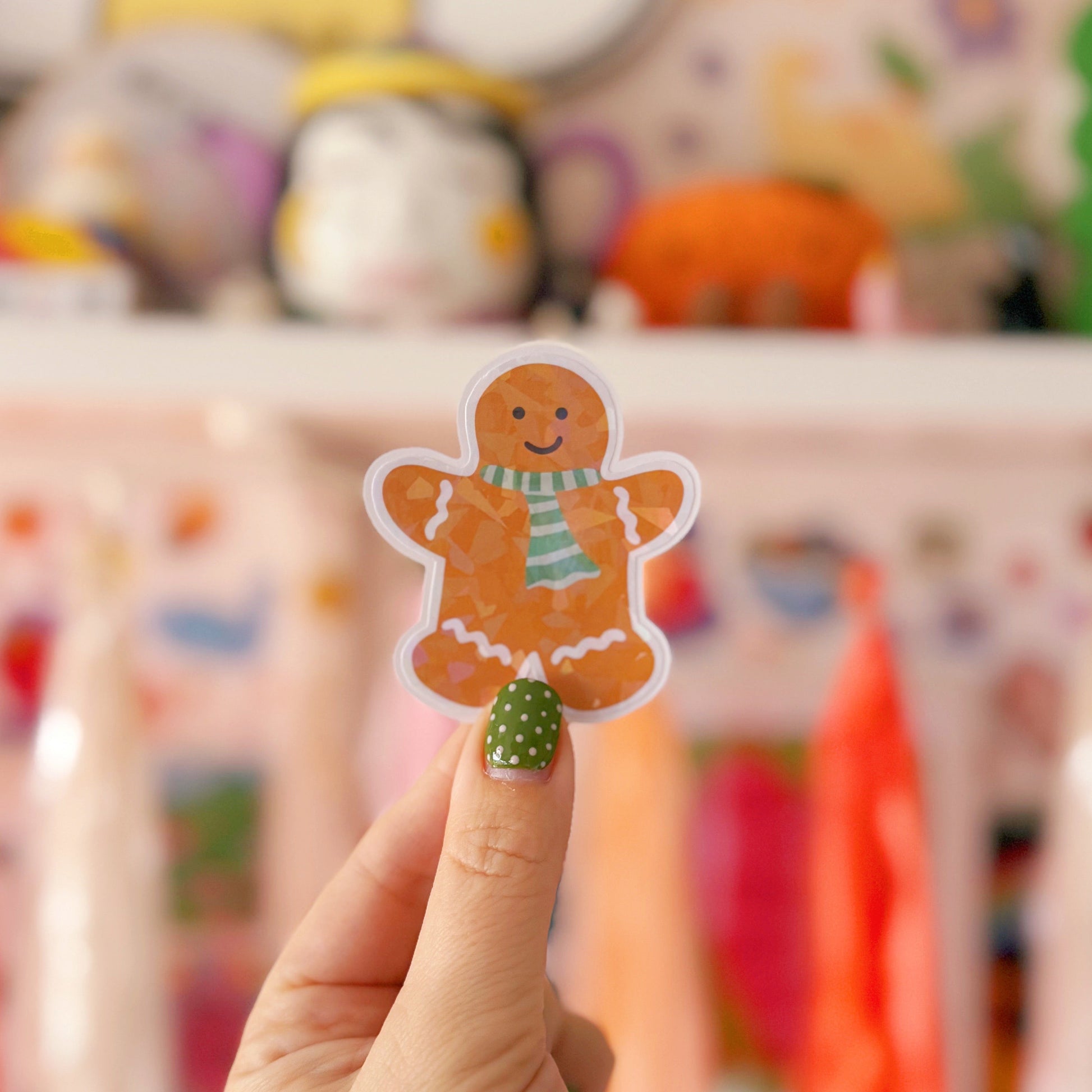 Hand holding a gingerbread man sticker with a colorful blurred background